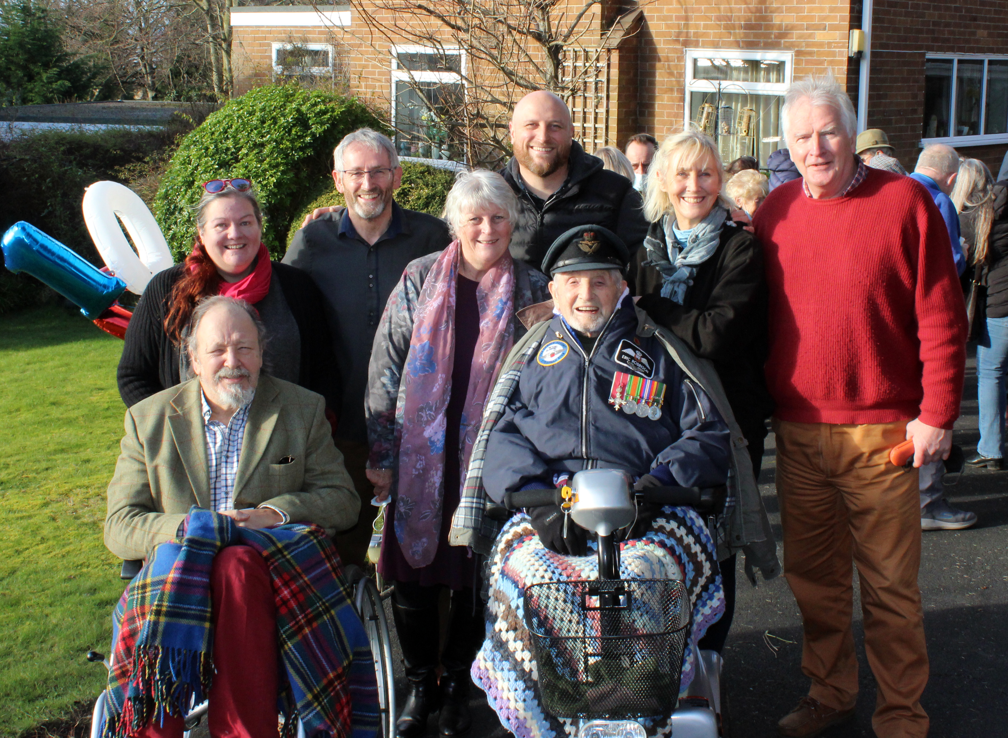 Eric in wheelchair outside, with family.