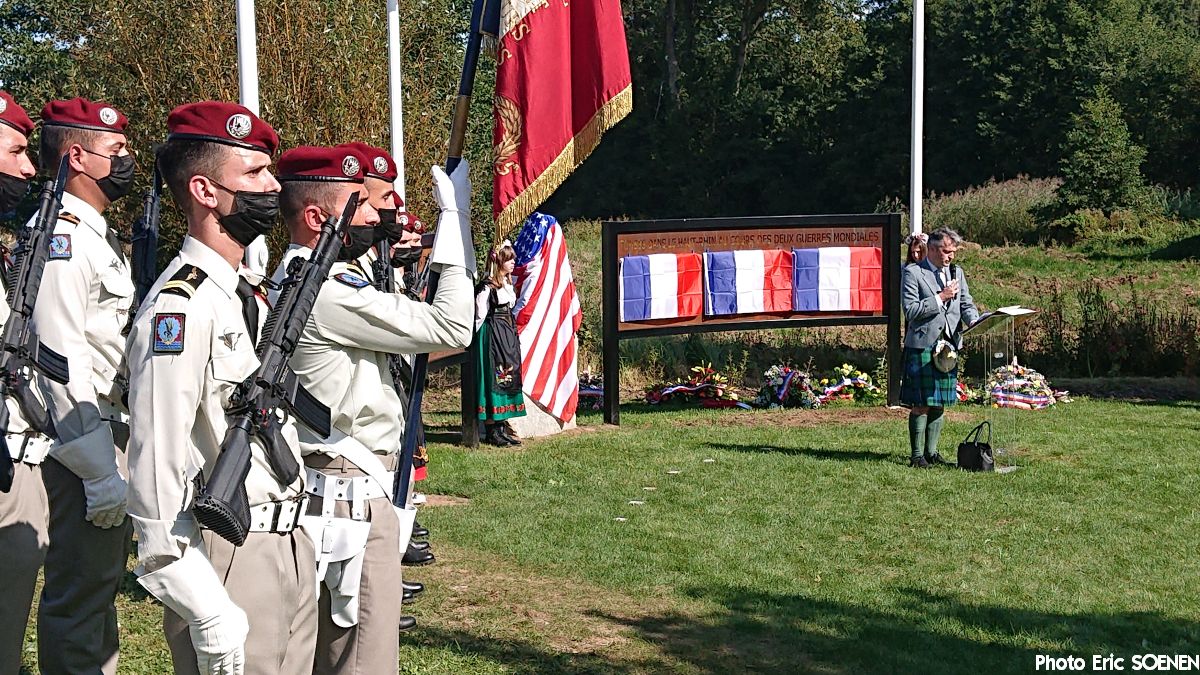 Personnel stand by memorial with speech stand.