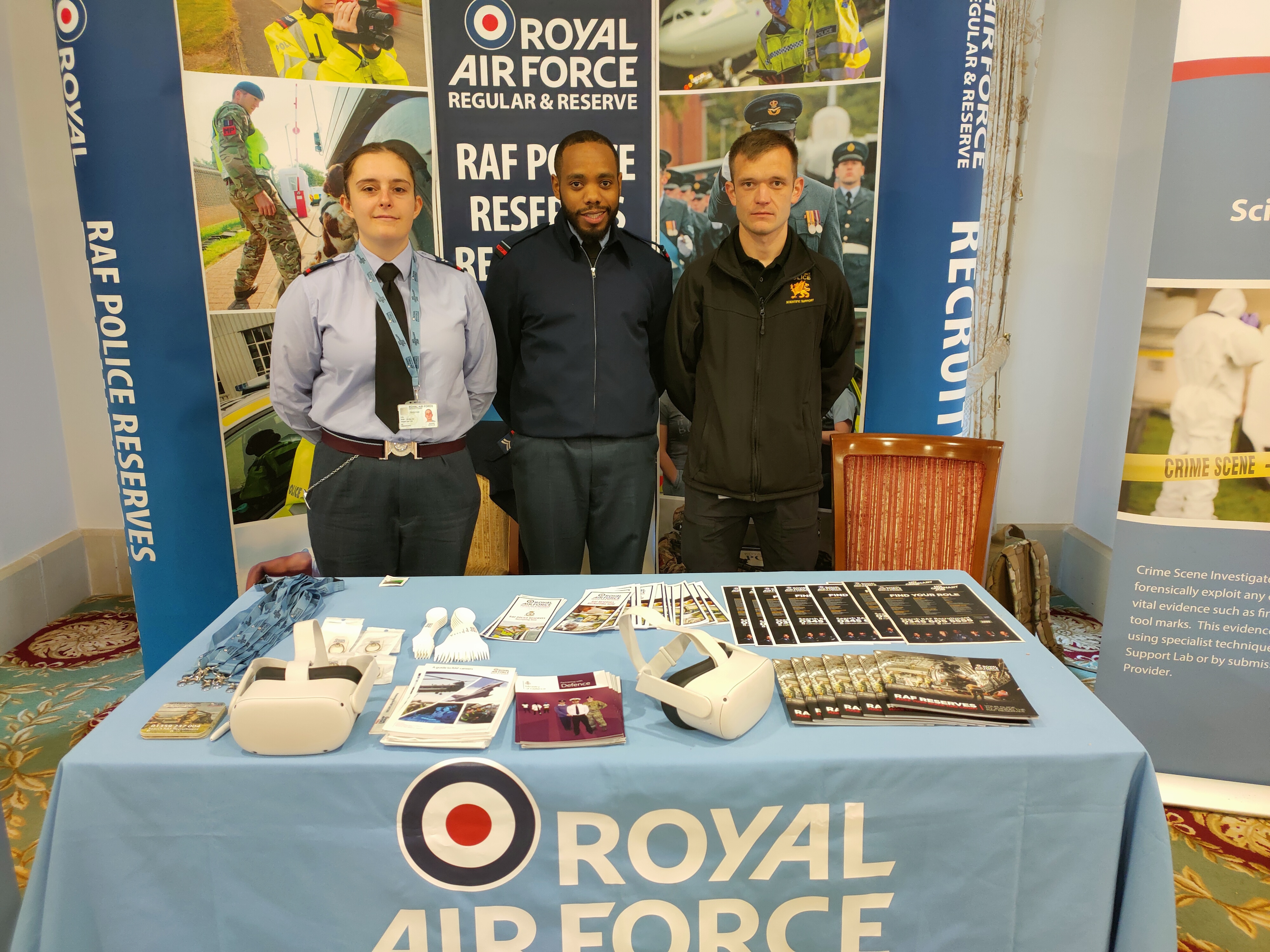 Personnel stand in-front of board and by table.