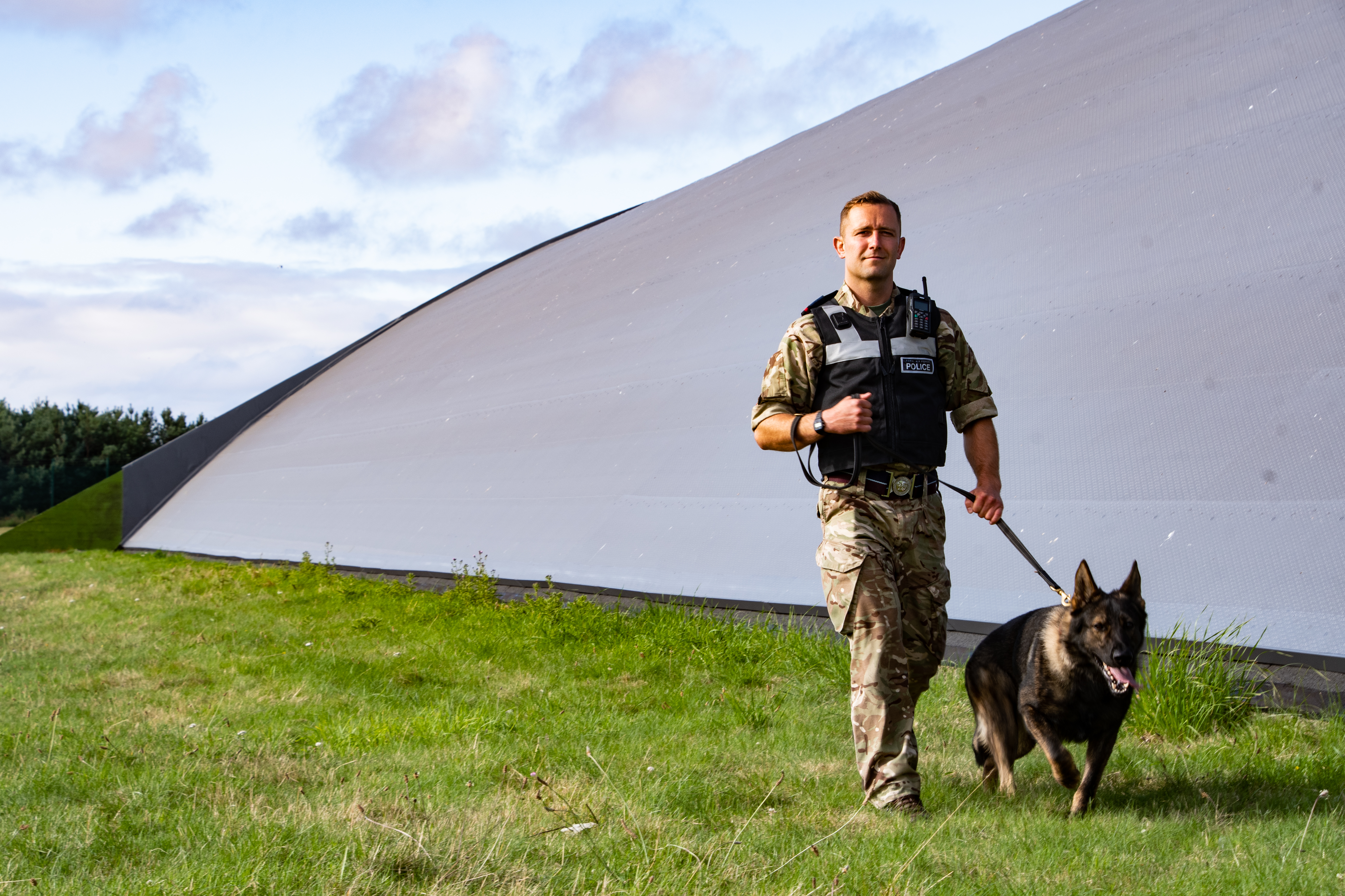 RAF Police Handler and dog walk by building.