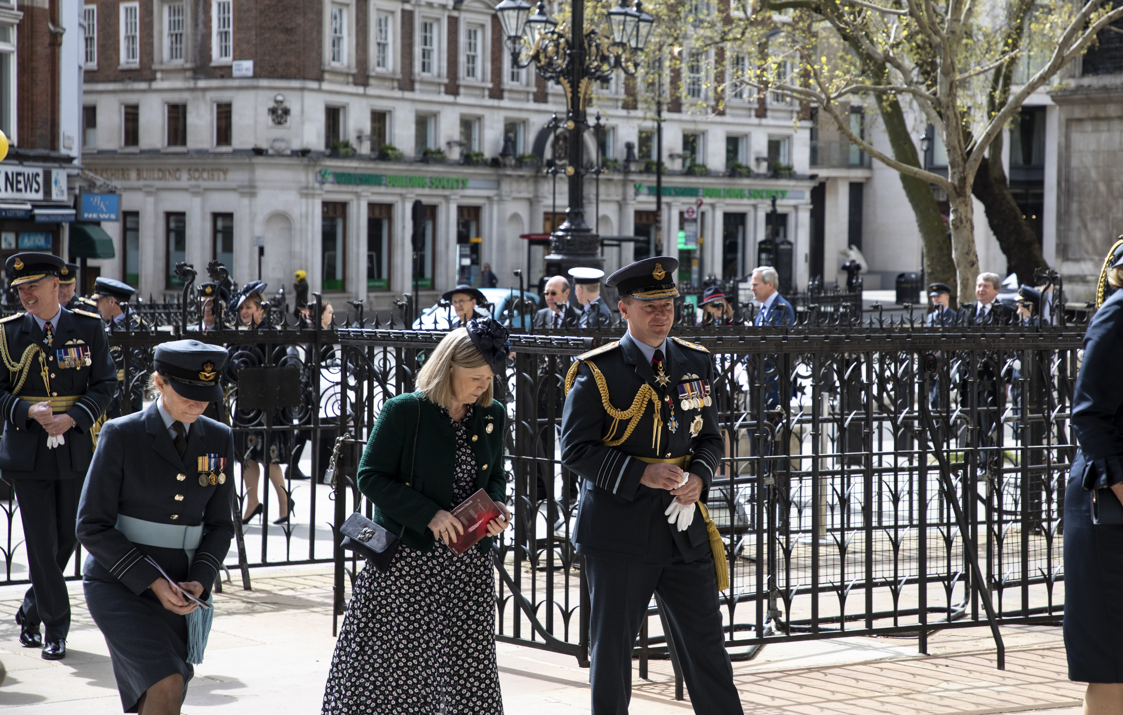 Chief of the Air Staff with wife and other personnel walk through metal gates to church.