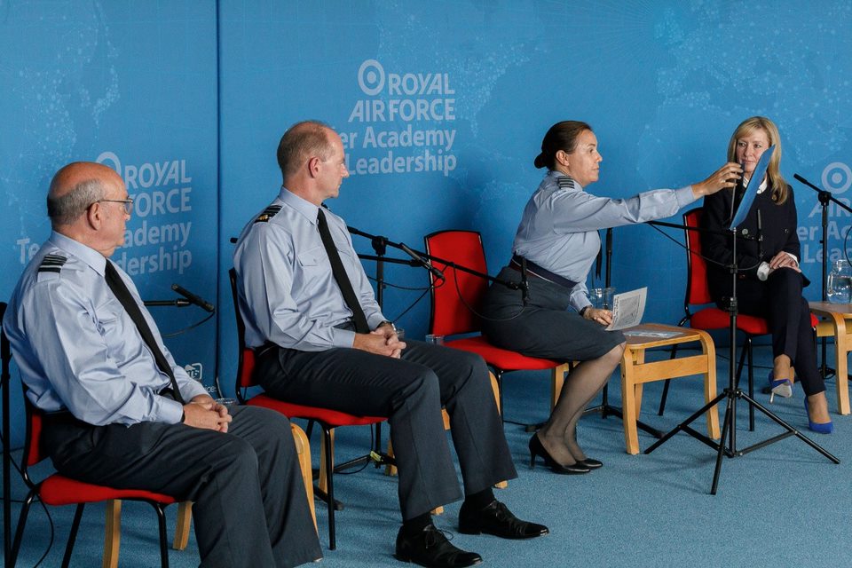 Speakers sit on chairs before microphones.