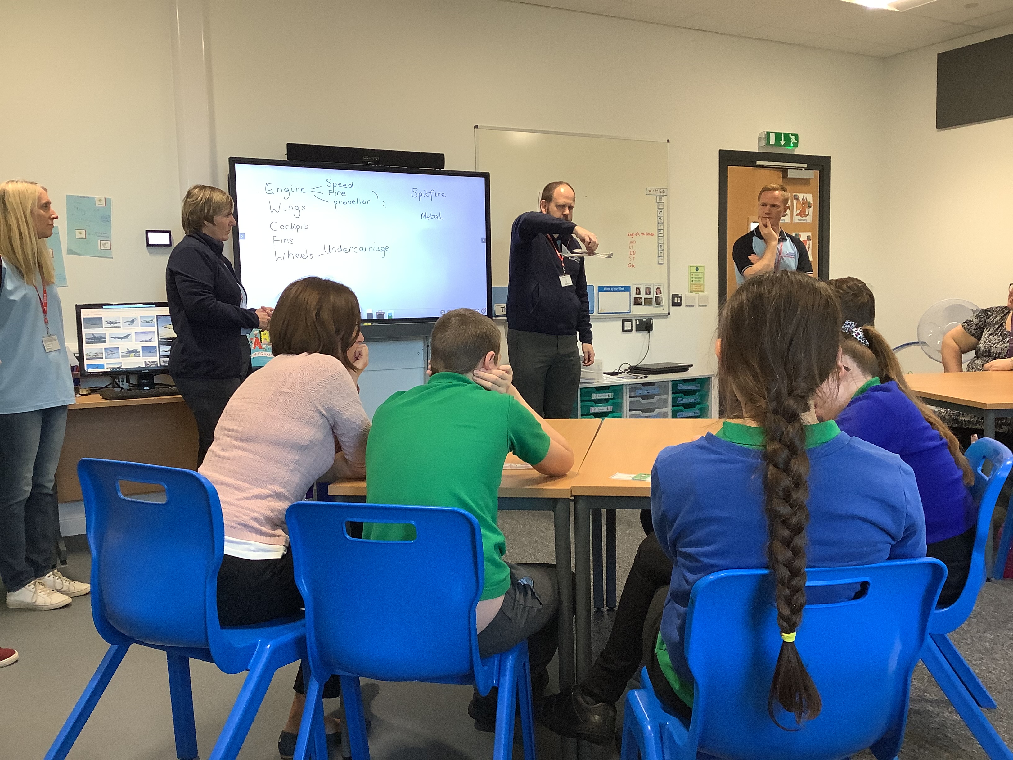 School children sit around a classroom table while the Team present.