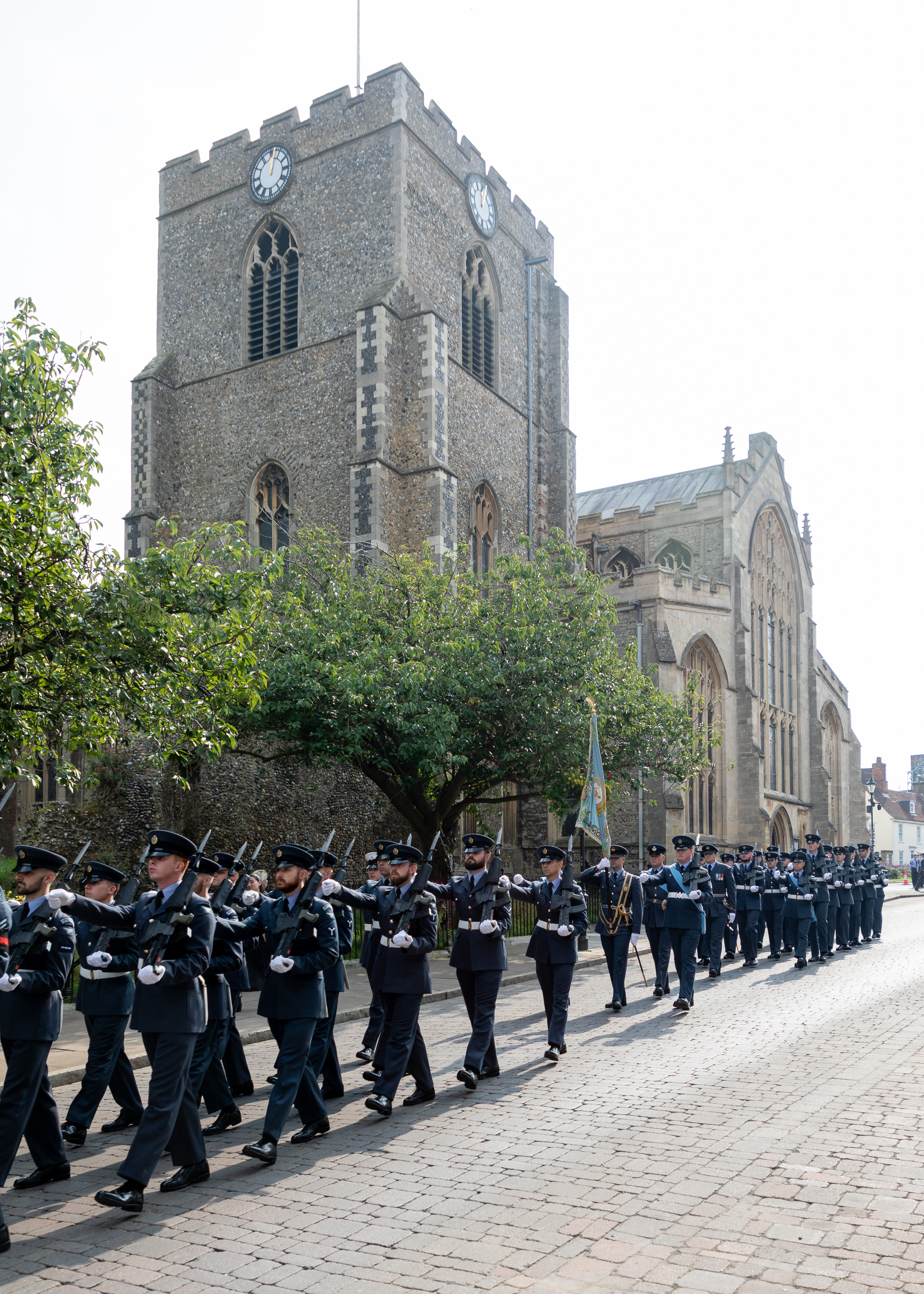 Personnel parade in town square, with colour flag.