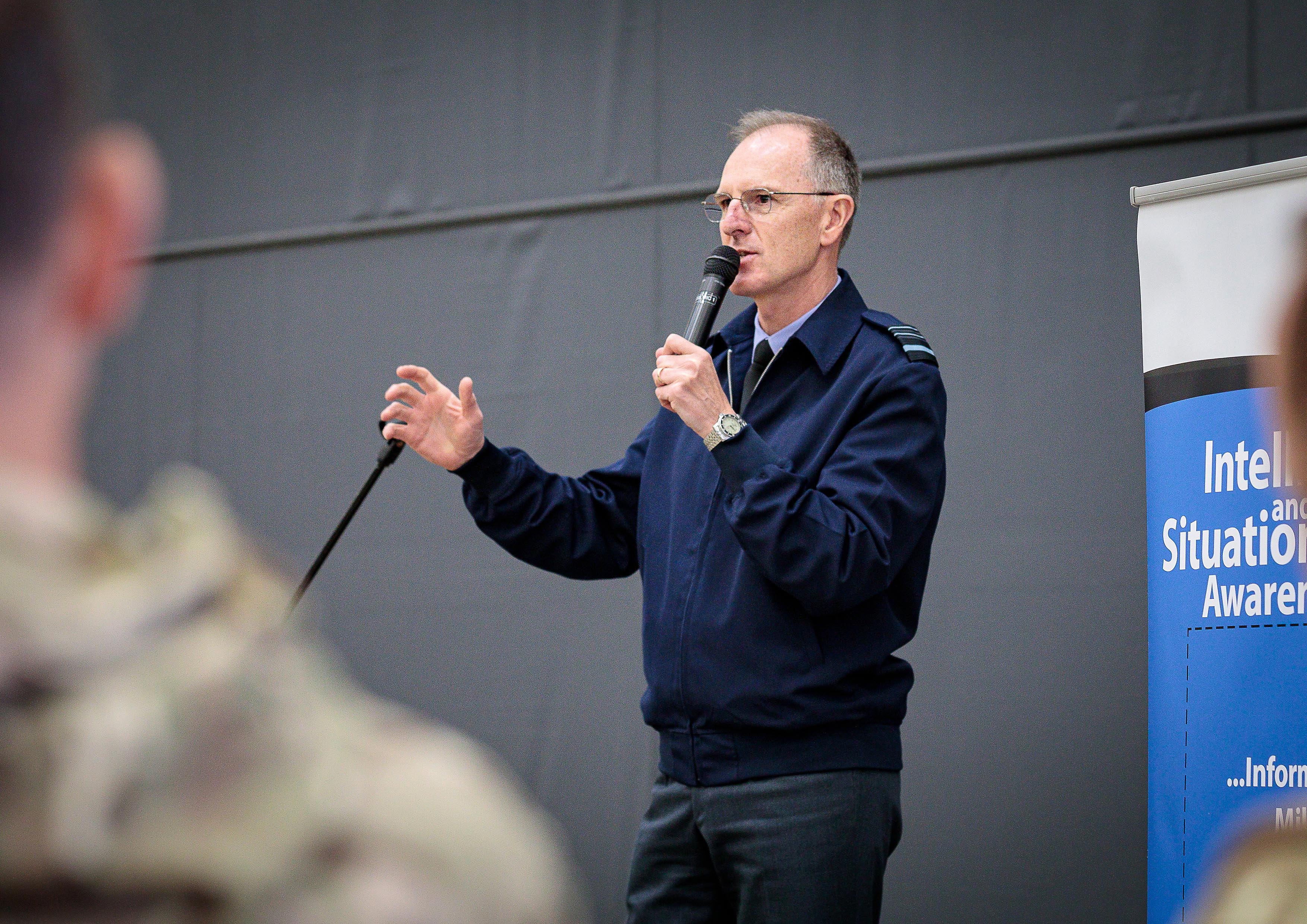 Air Marshal hold microphone while giving presentation.