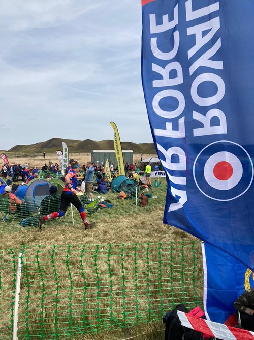 Orienteer runs on grass before spectators.