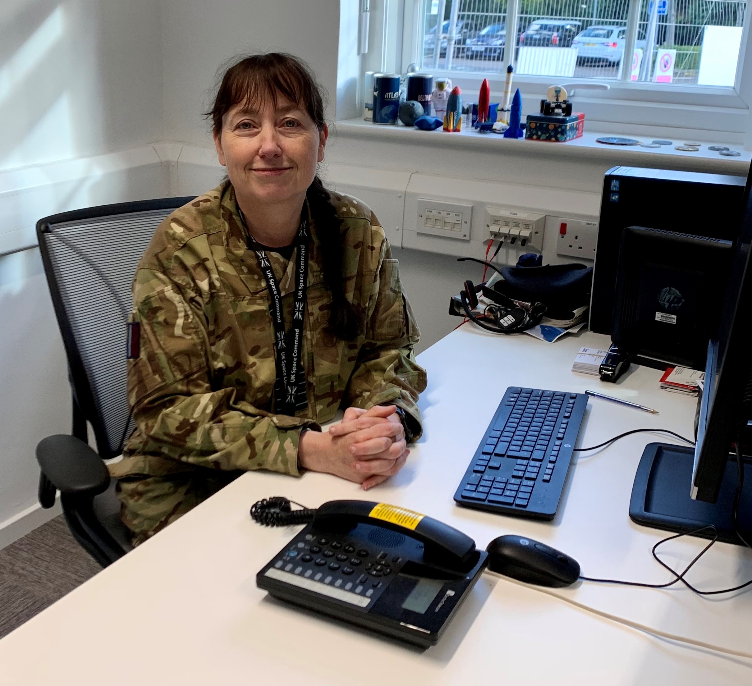 Group Captain Rayna Owens sits at a computer desk. 