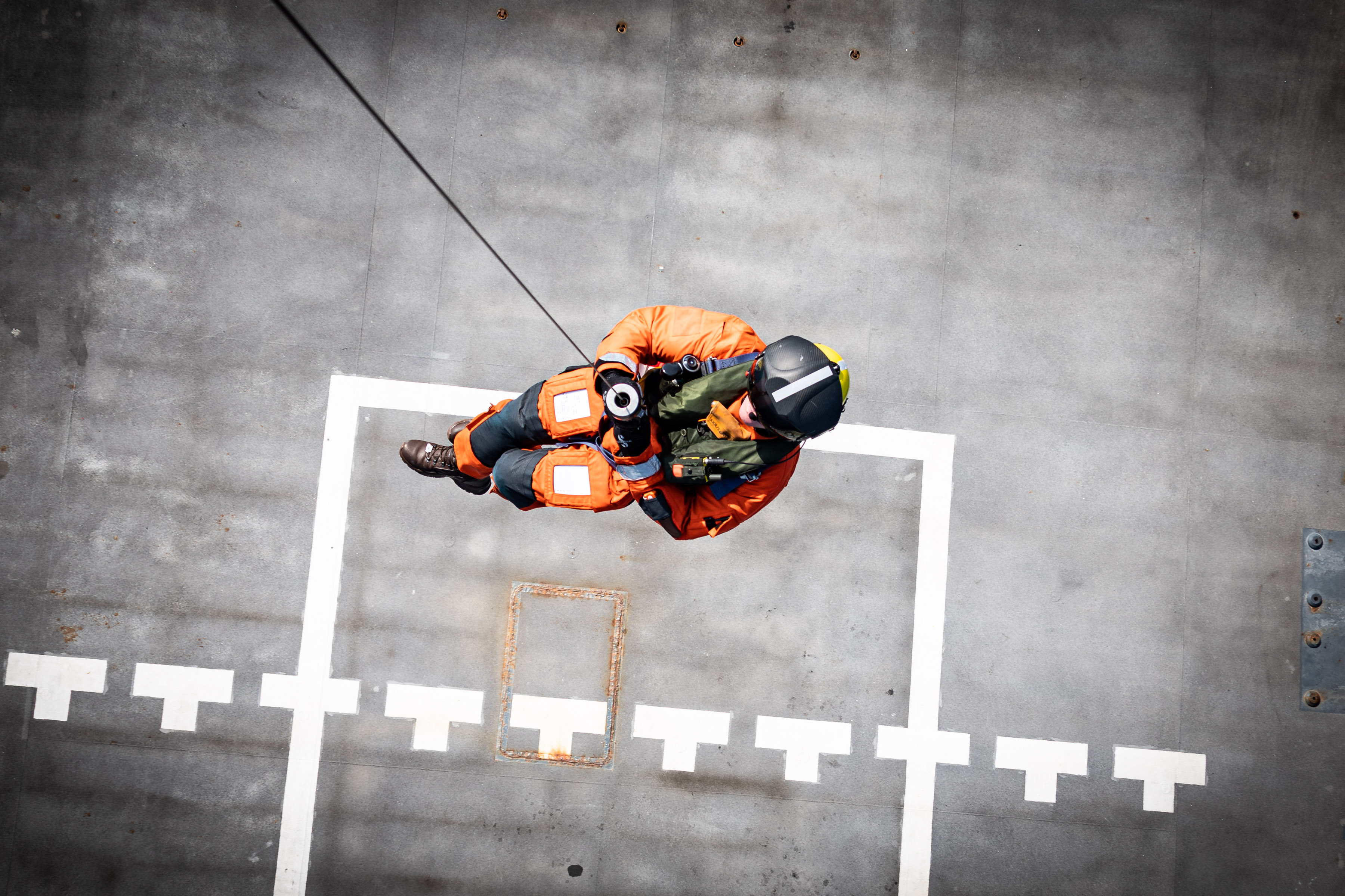 Personnel zipping towards helicopter landing pad.