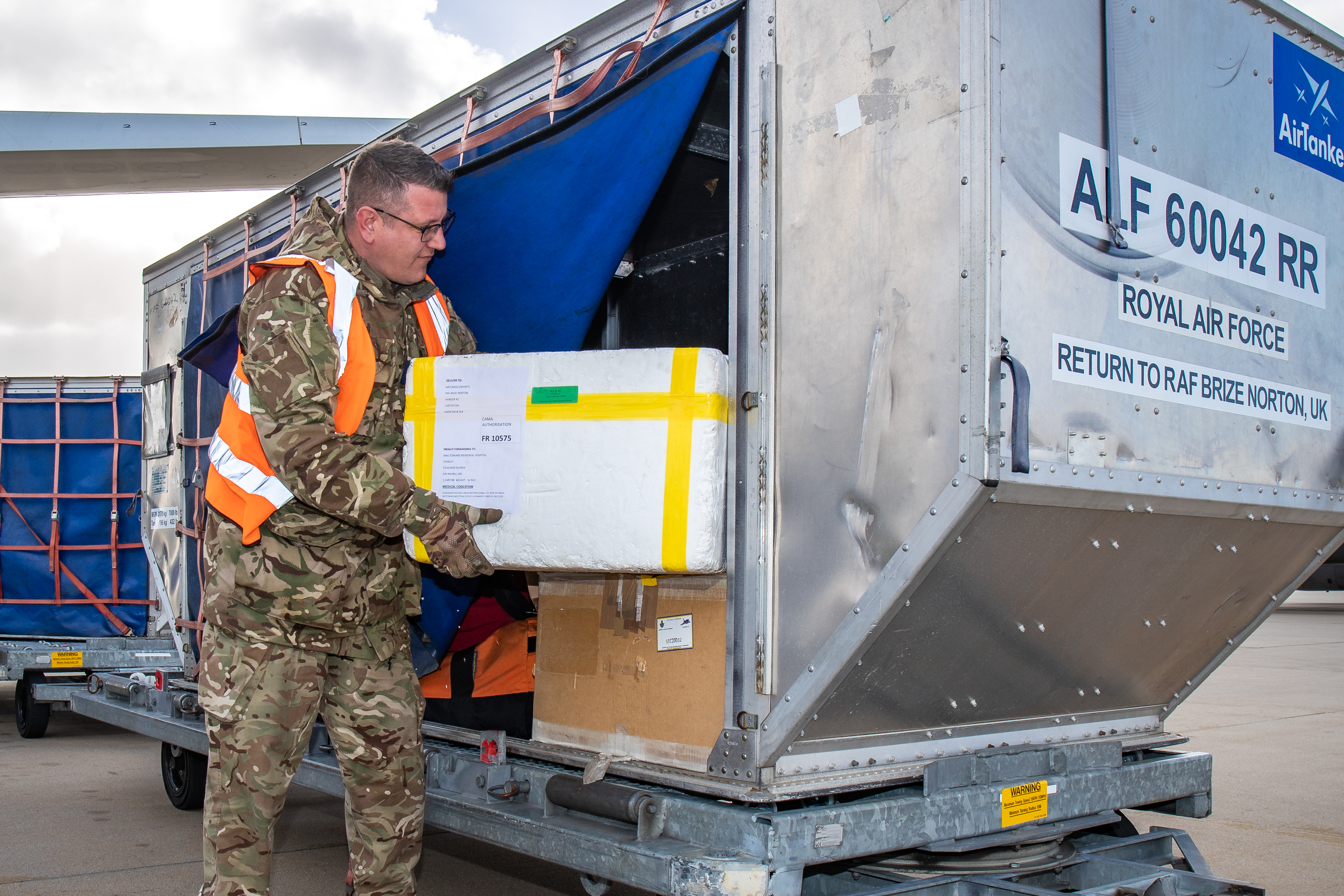 Personnel loads boxes into metal cargo container. 