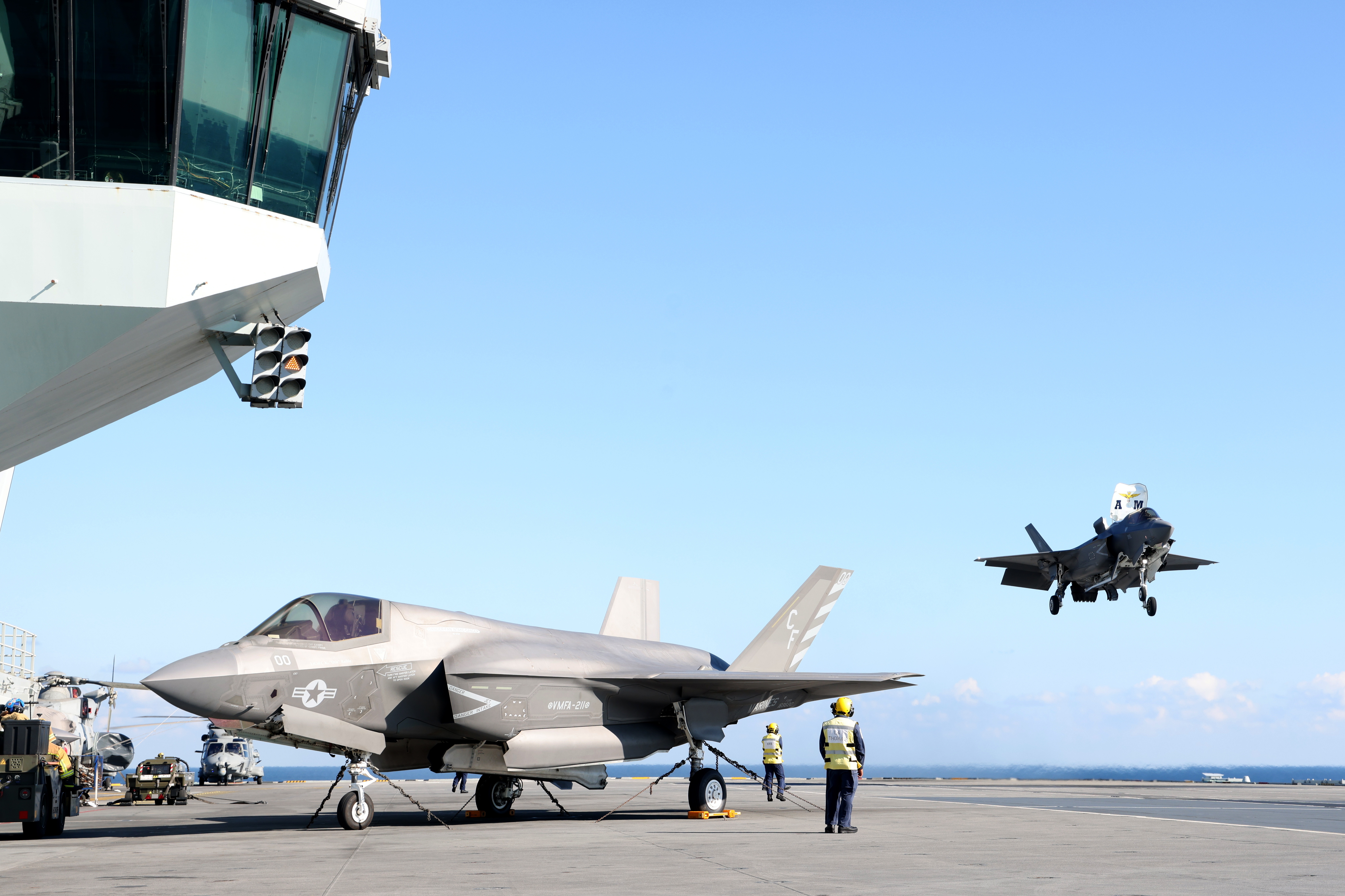 Aircraft on the carrier and one coming in to land.