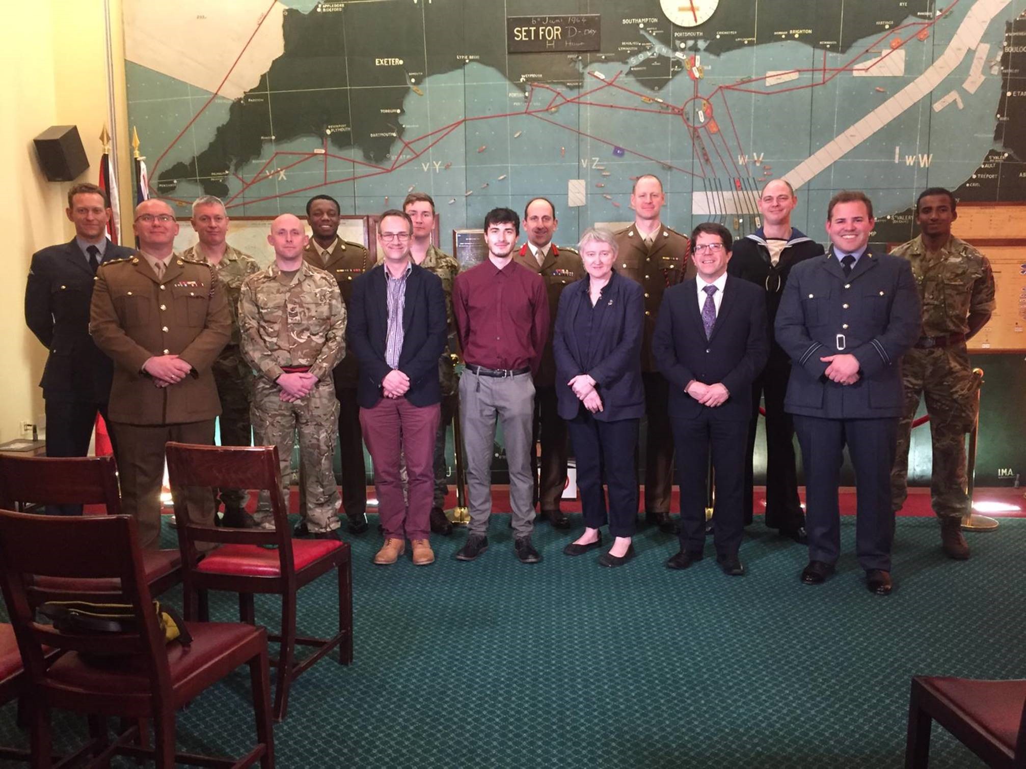 Personnel and notable figures stand in conference room.