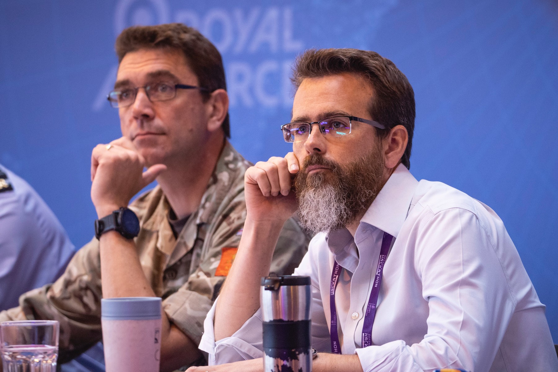 Image shows Armed Force personnel sit at a table.