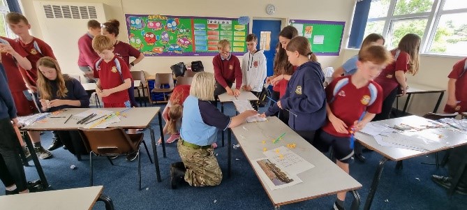 Image shows school pupils building their models on tables with RAF STEM Ambassadors.