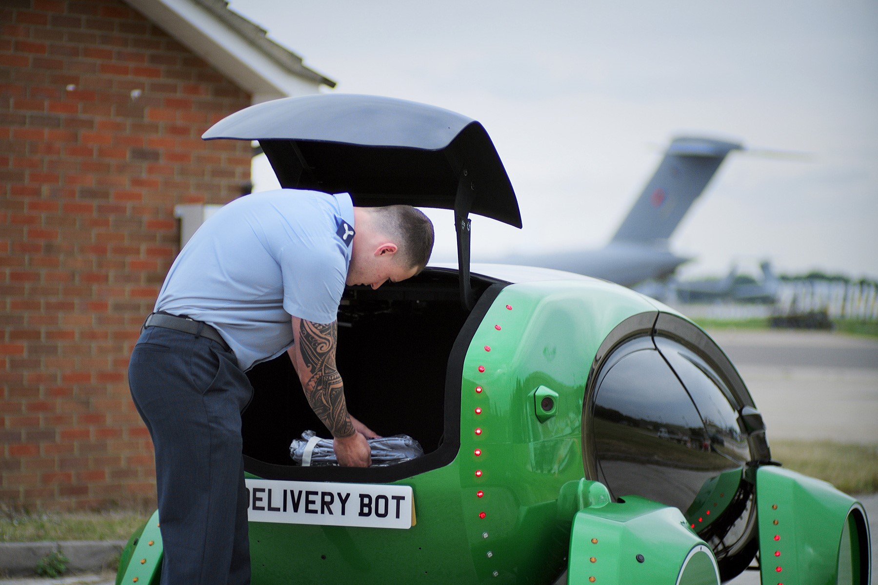 Personnel takes supplies from boot of robot car.