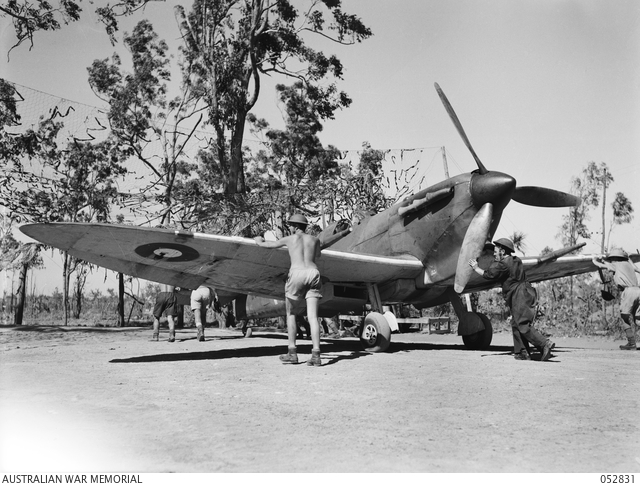 Black and white image of RAF pilot pushing the wing of a Spitfire on the airfield.