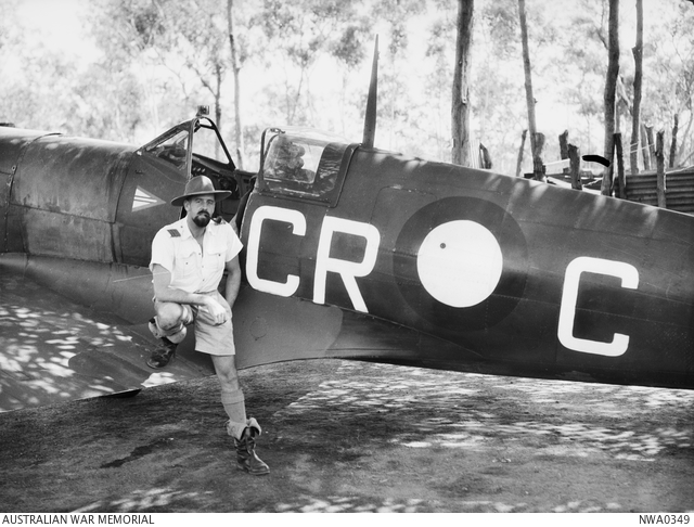 Black and white image of RAF pilot sitting on the wing of a Spitfire on the airfield.