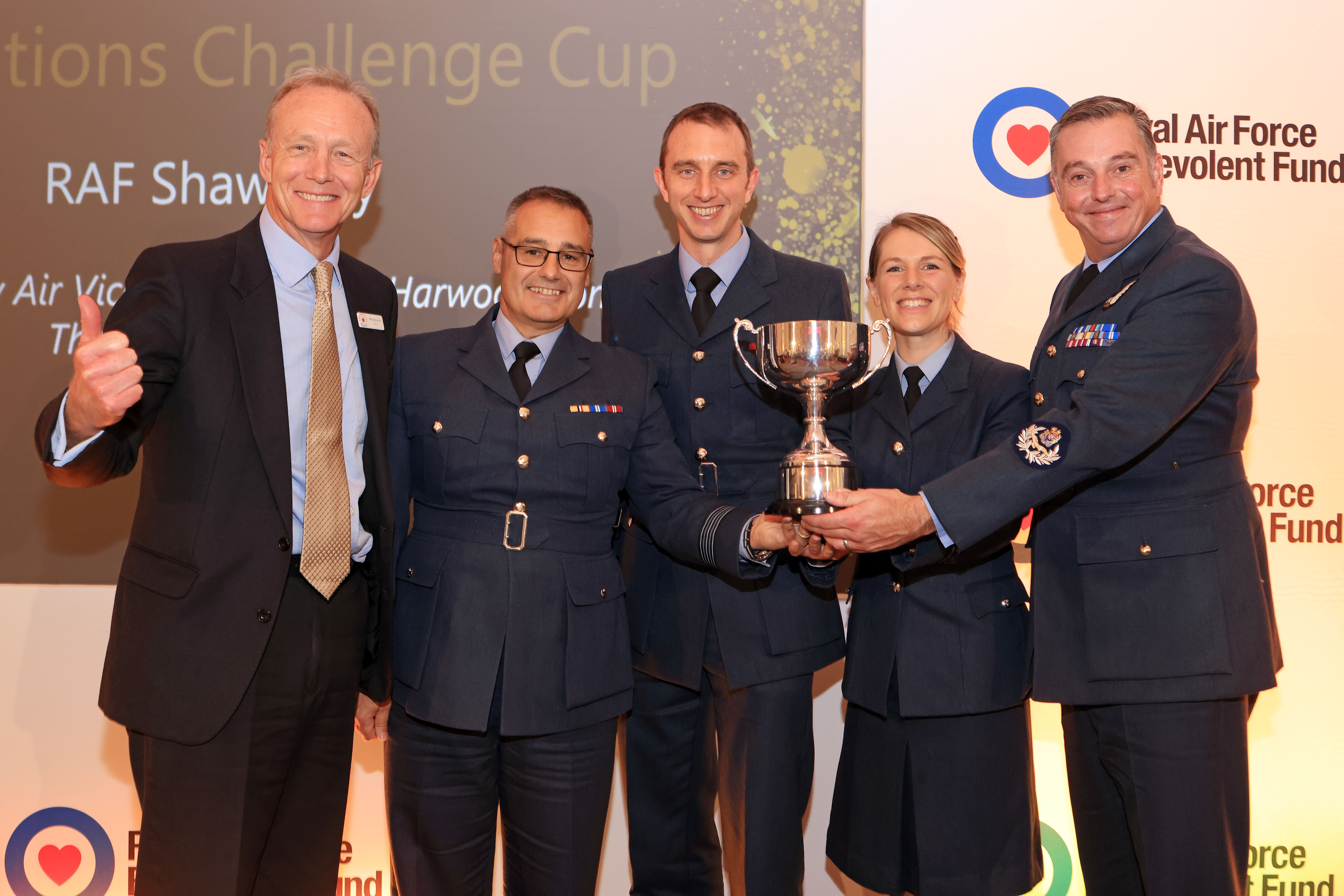 Personnel hold their award; a trophy.