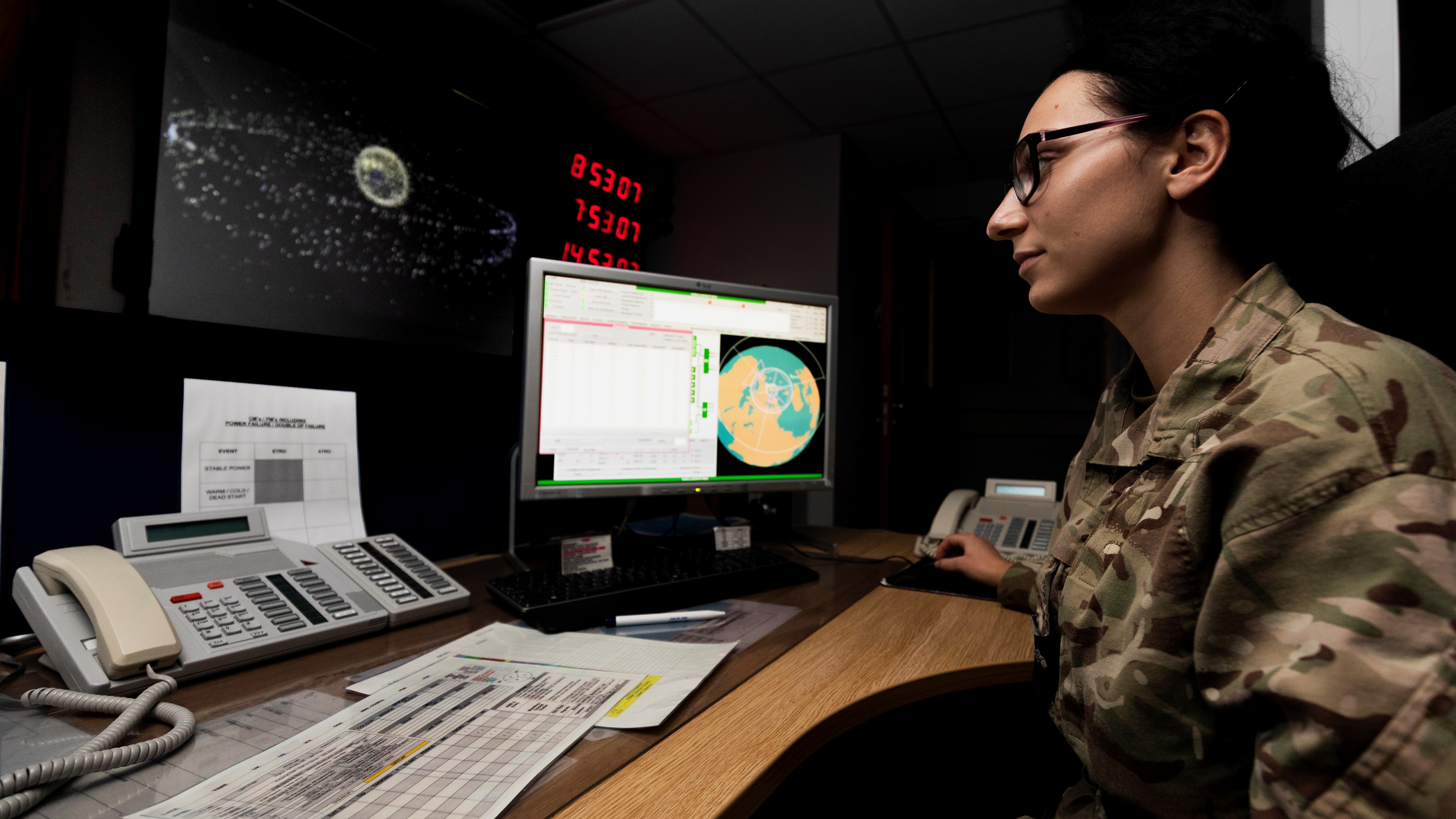 Operator sits at computer and desk.