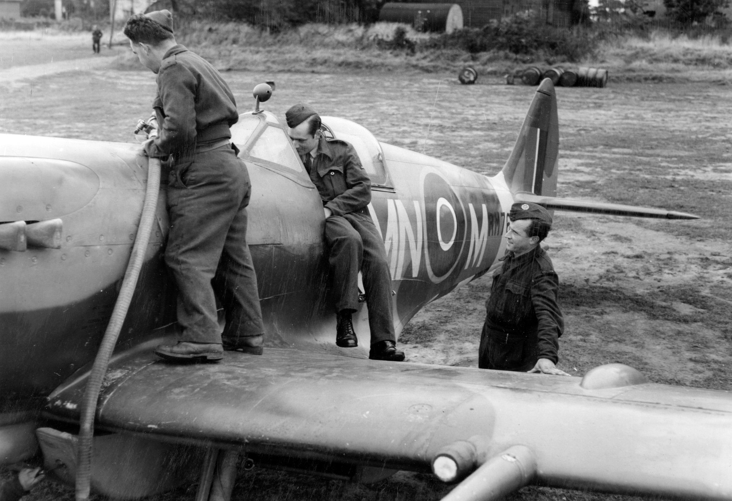 Three airmen refuel a Spitfire.