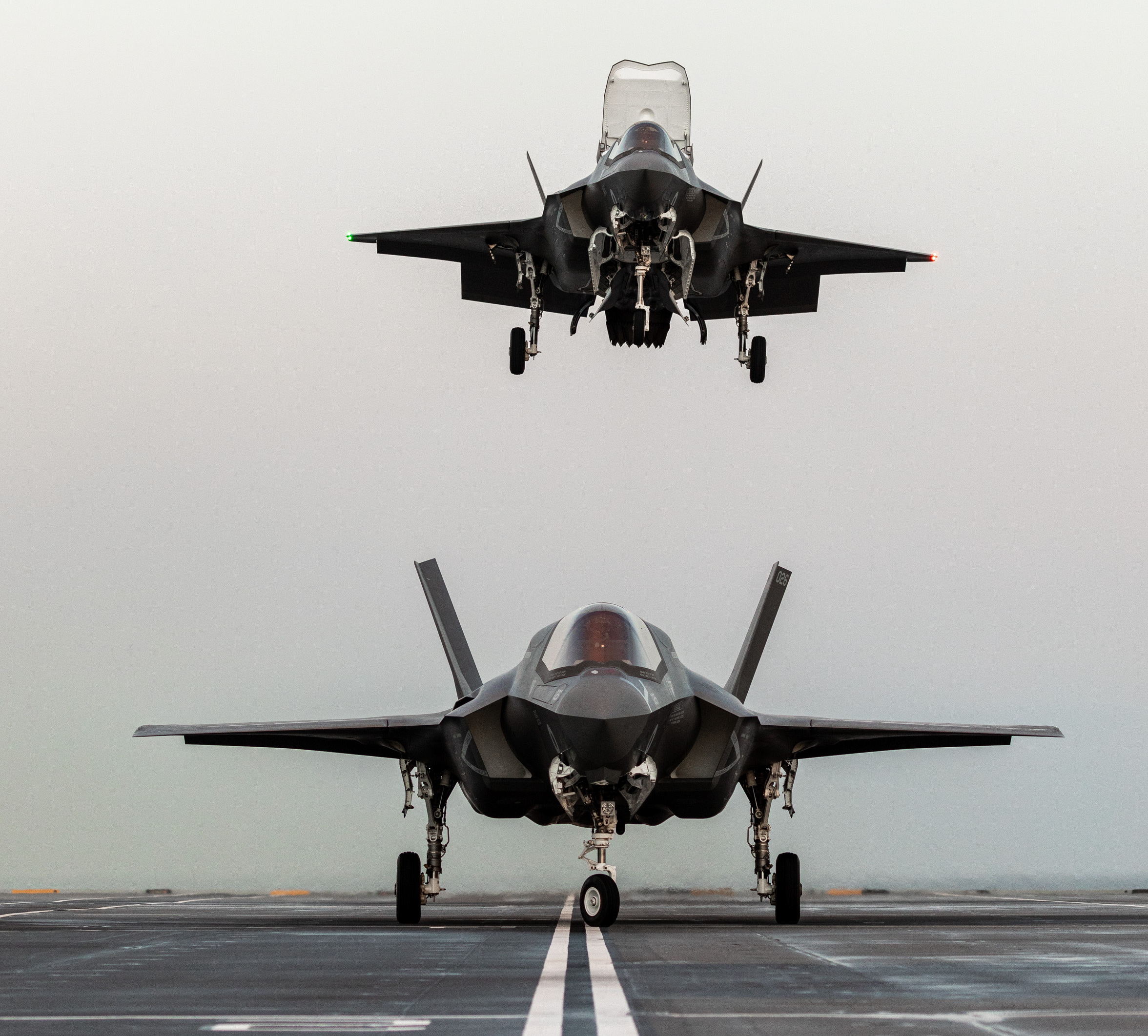 Image shows a RAF Typhoon on the runway as another Typhoon flies overhead.