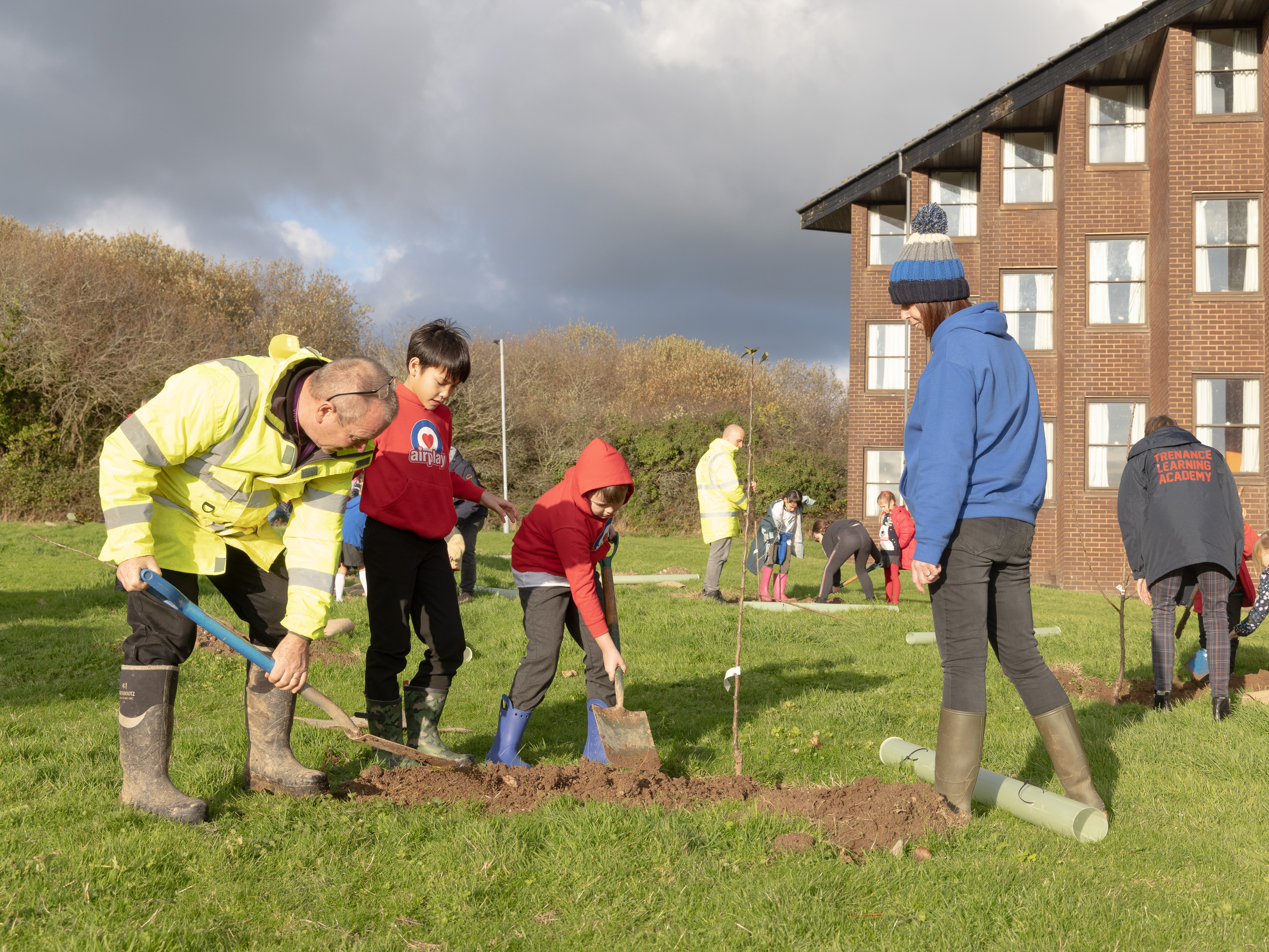 Image shows community and RAF aviators planting young trees and digging with spades.