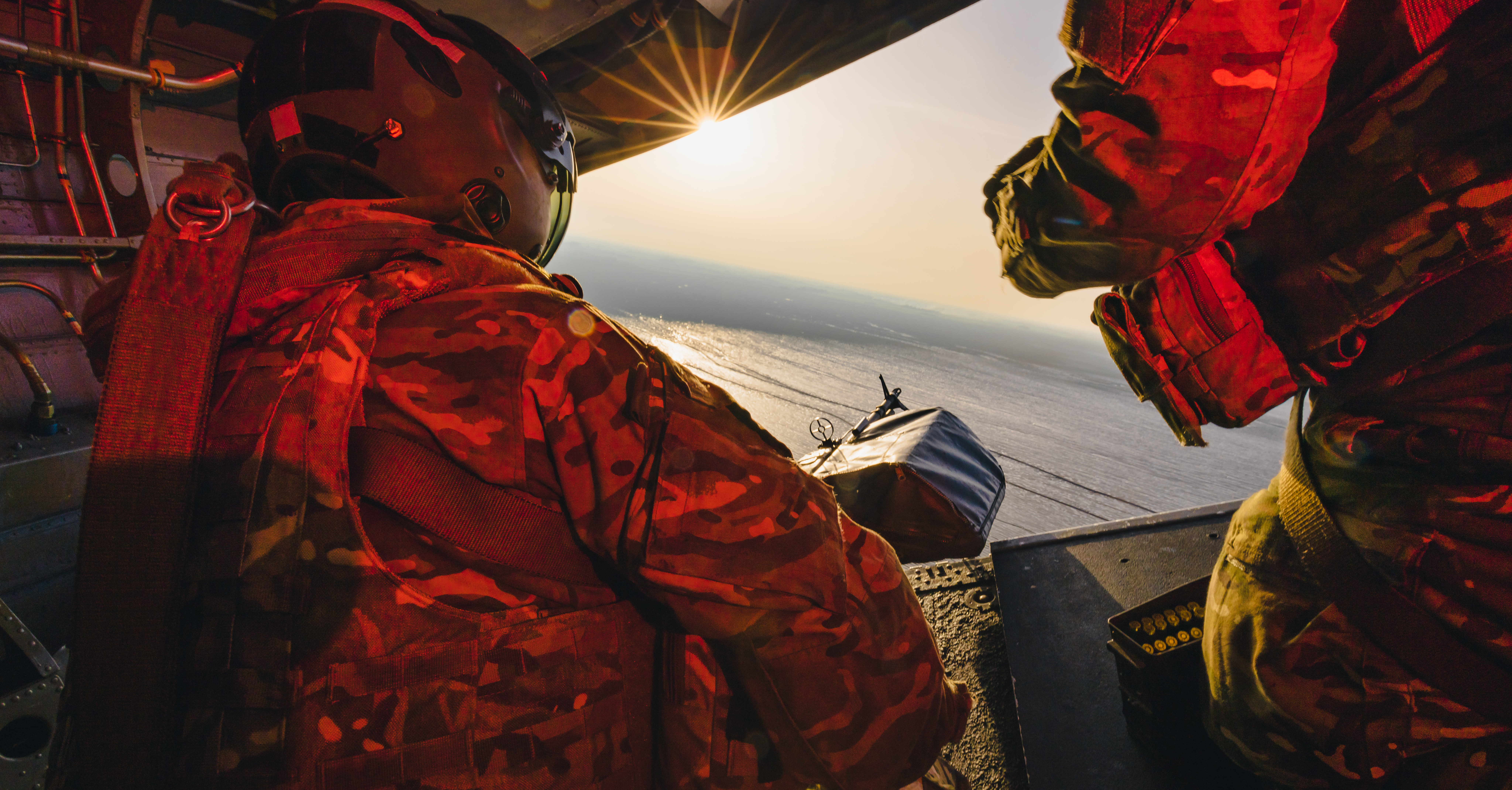 Image shows RAF Gunner manning machine gun from the back of a Chinook while it is in flight.