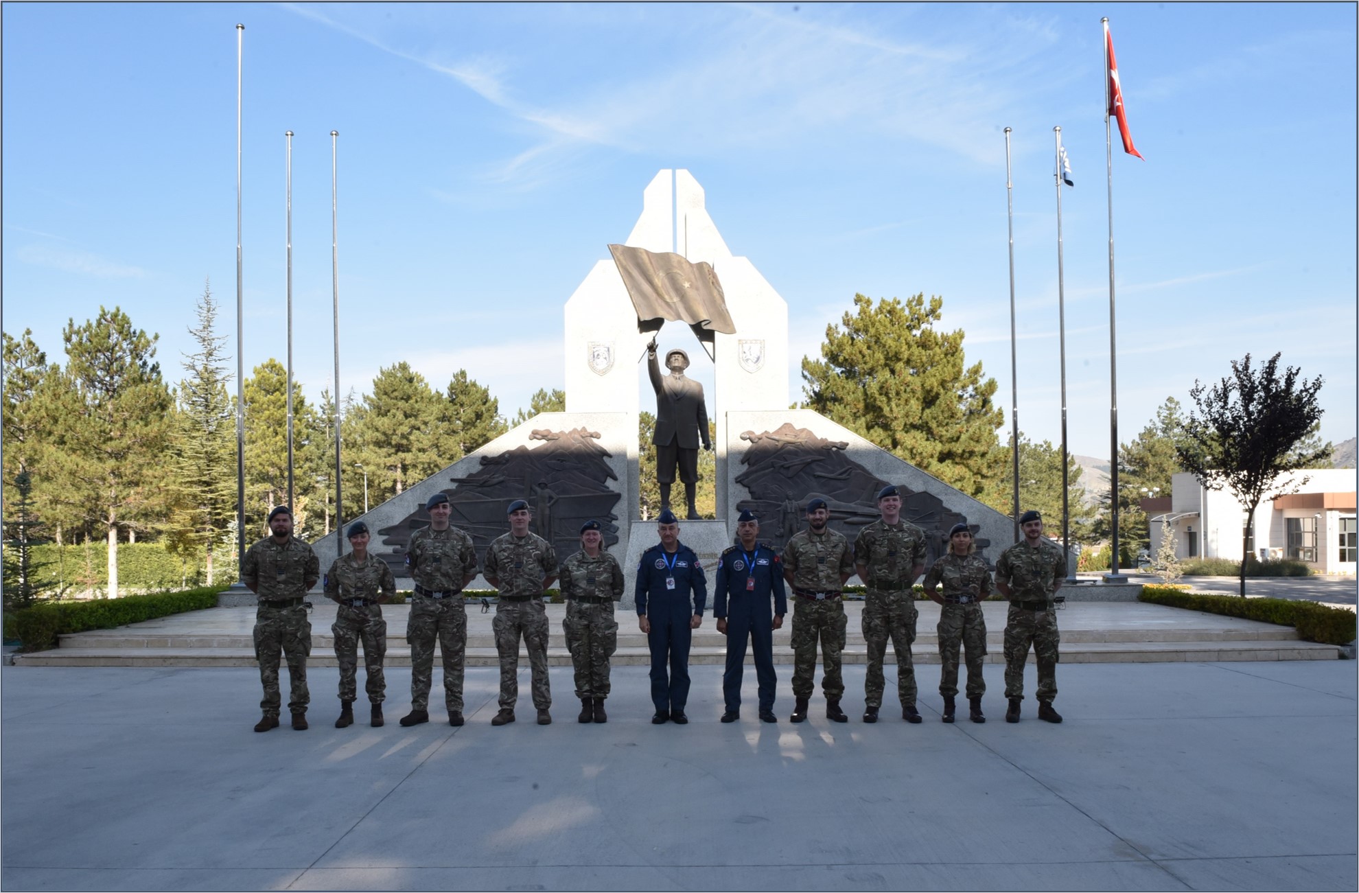 Image shows personnel standing by memorial statue with figure of soldier in the middle..