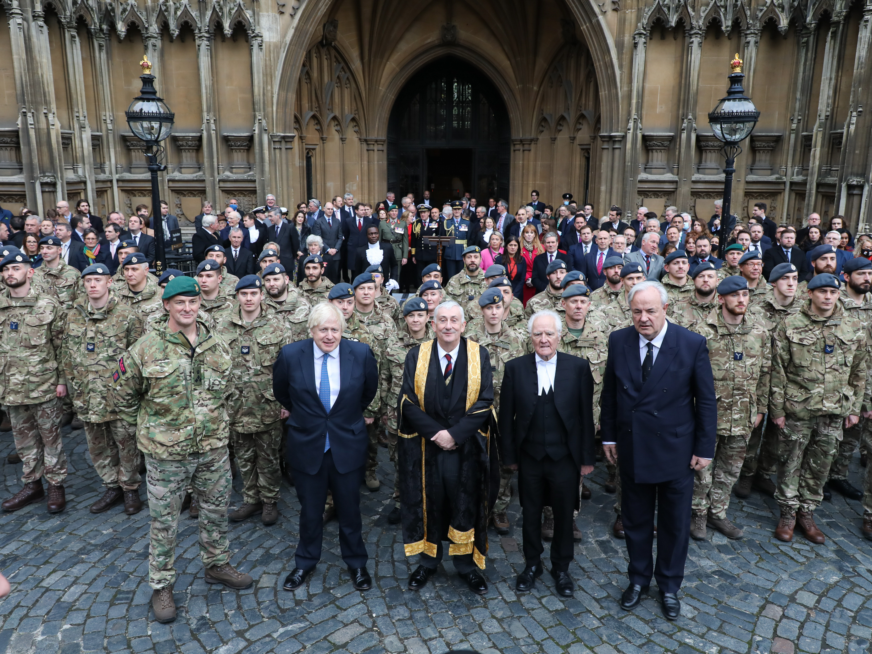 Armed Forces stand outside Parliament with Prime Minister and other notable figures.