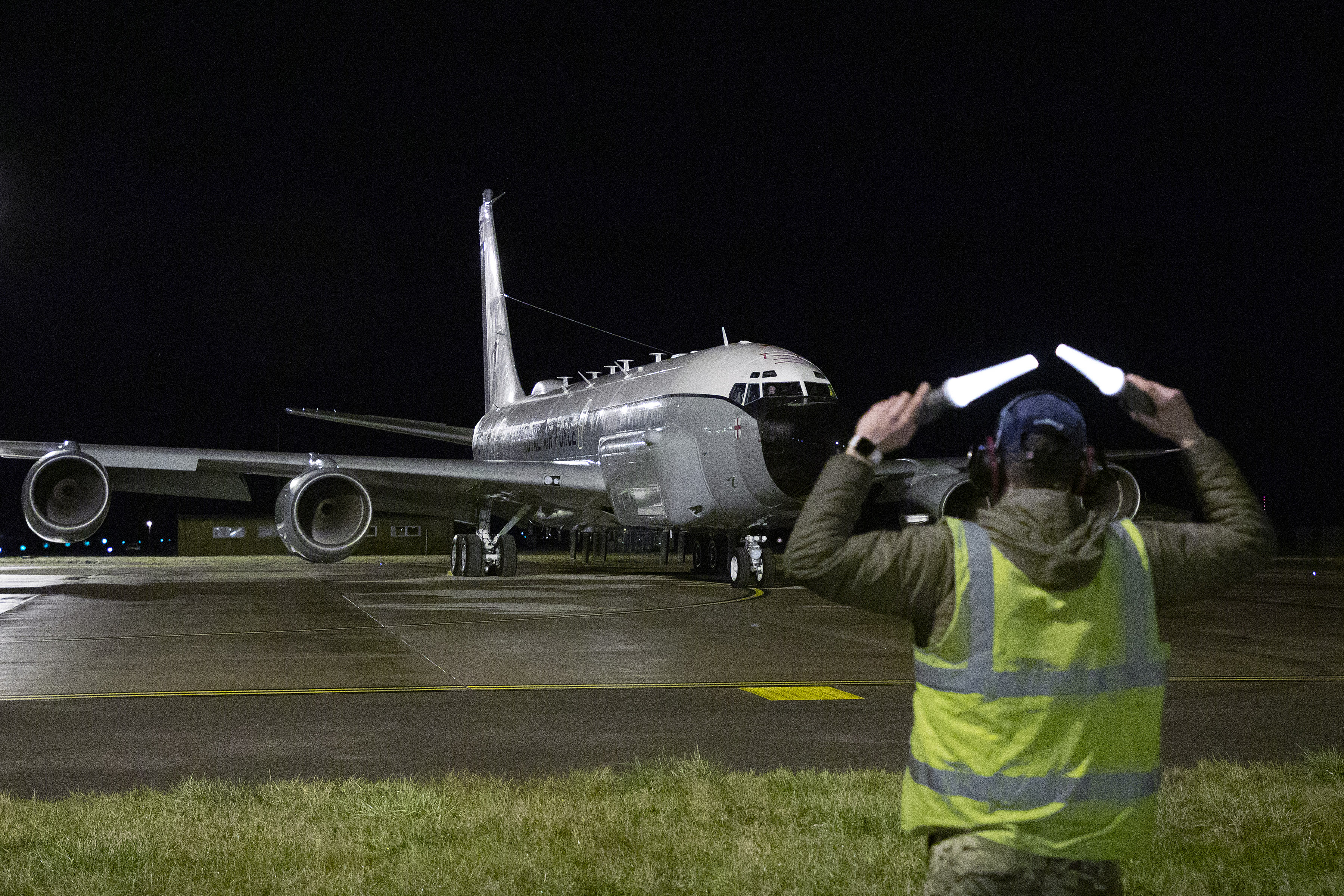 Rivet Joint aircraft guided at night by personnel.