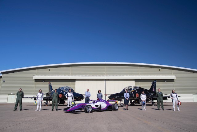 Personnel stand before two Hawk T2 aircrafts with F1 car.