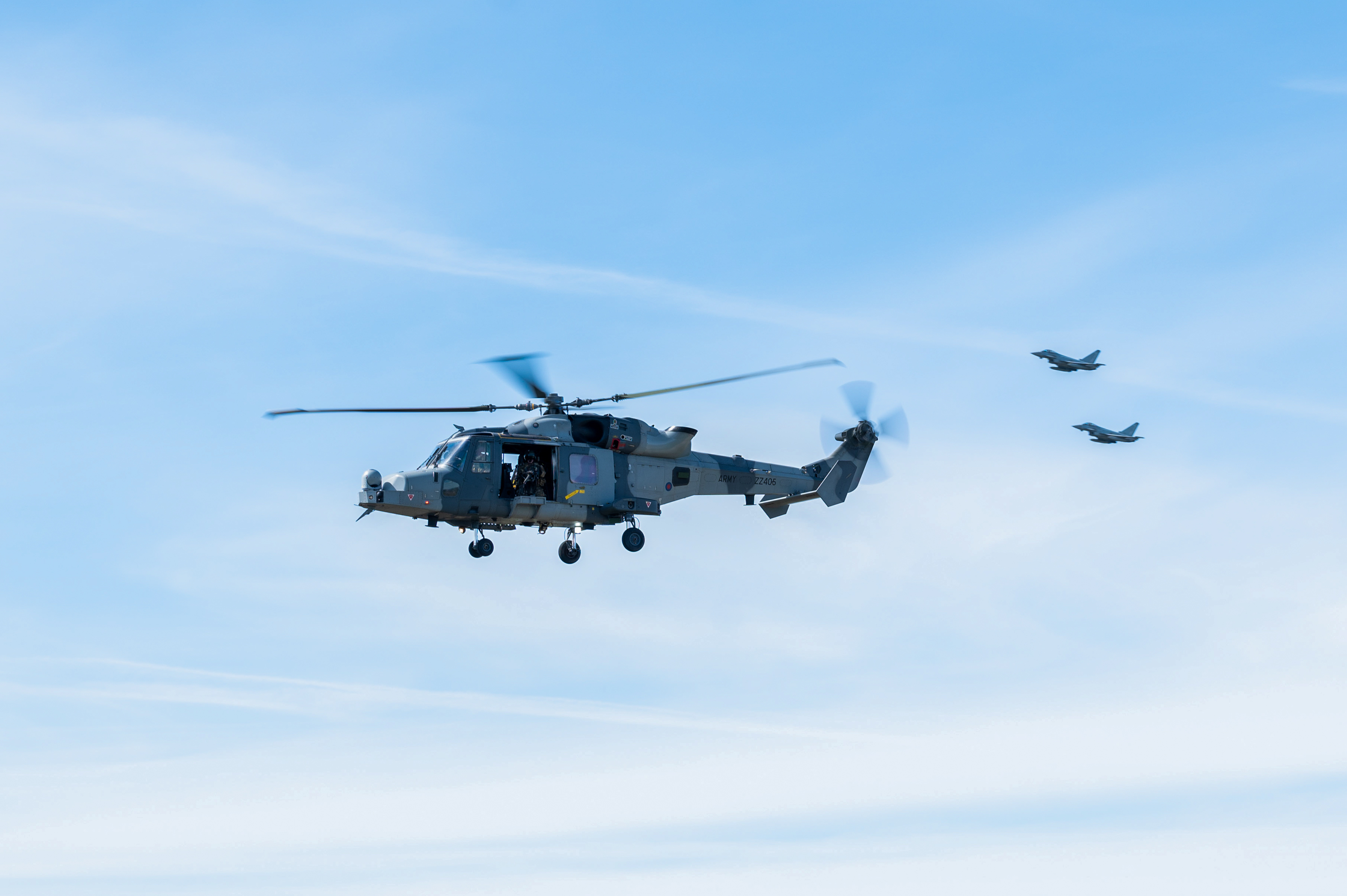 Two RAF Typhoons and a British Army Wildcat helicopter in flight.
