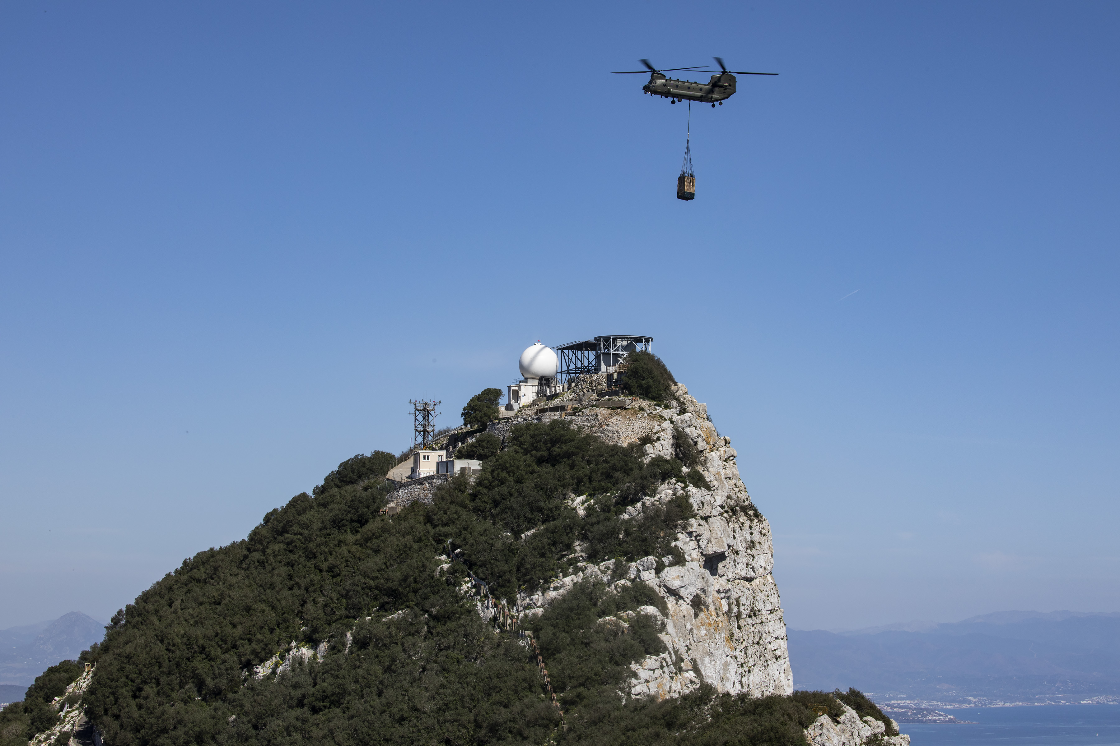 Chinook carries loaded sling over the Rock of Gibraltar.