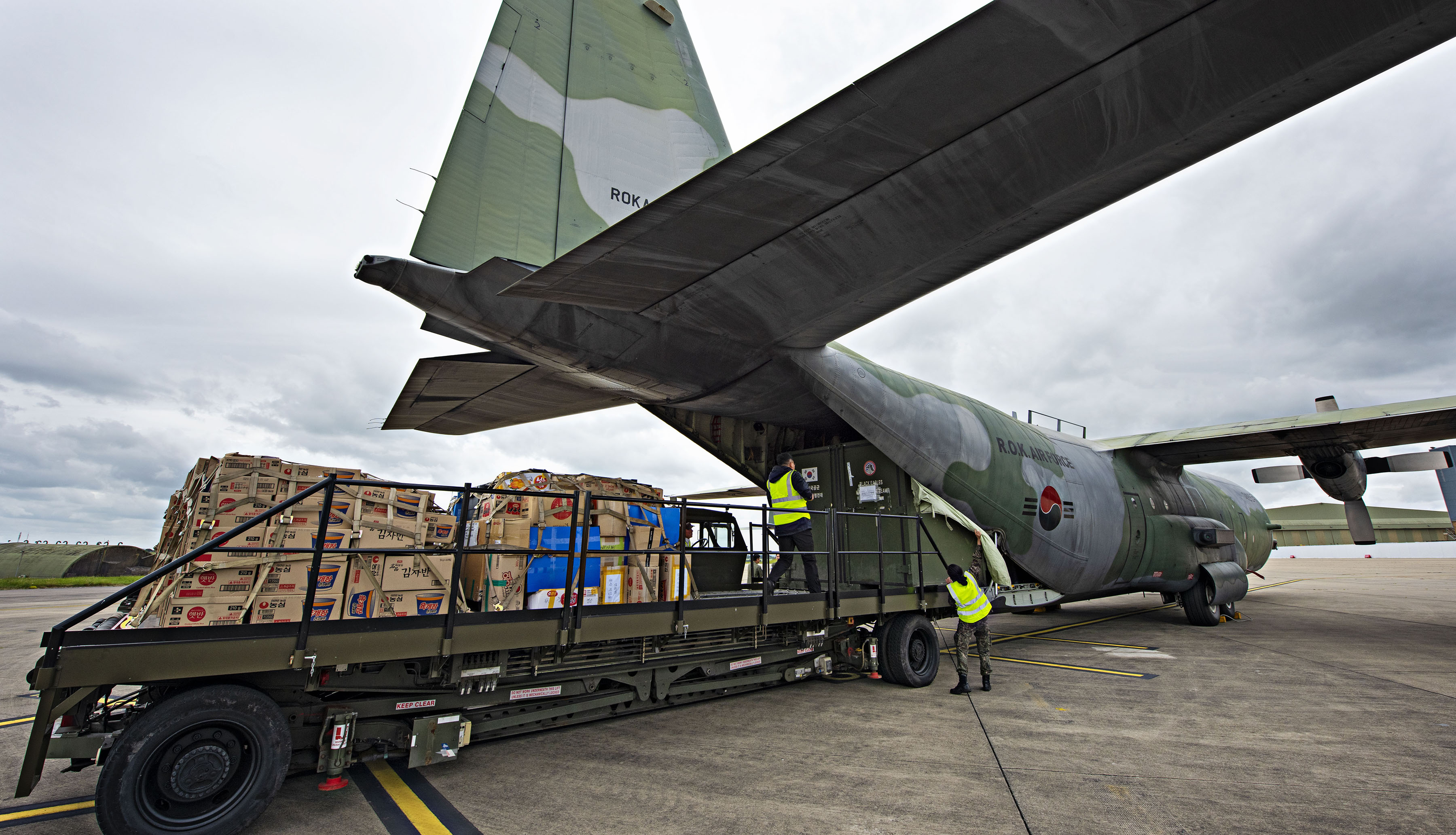 Image shows C-130 carrier aircraft with loading bay open and cargo. 