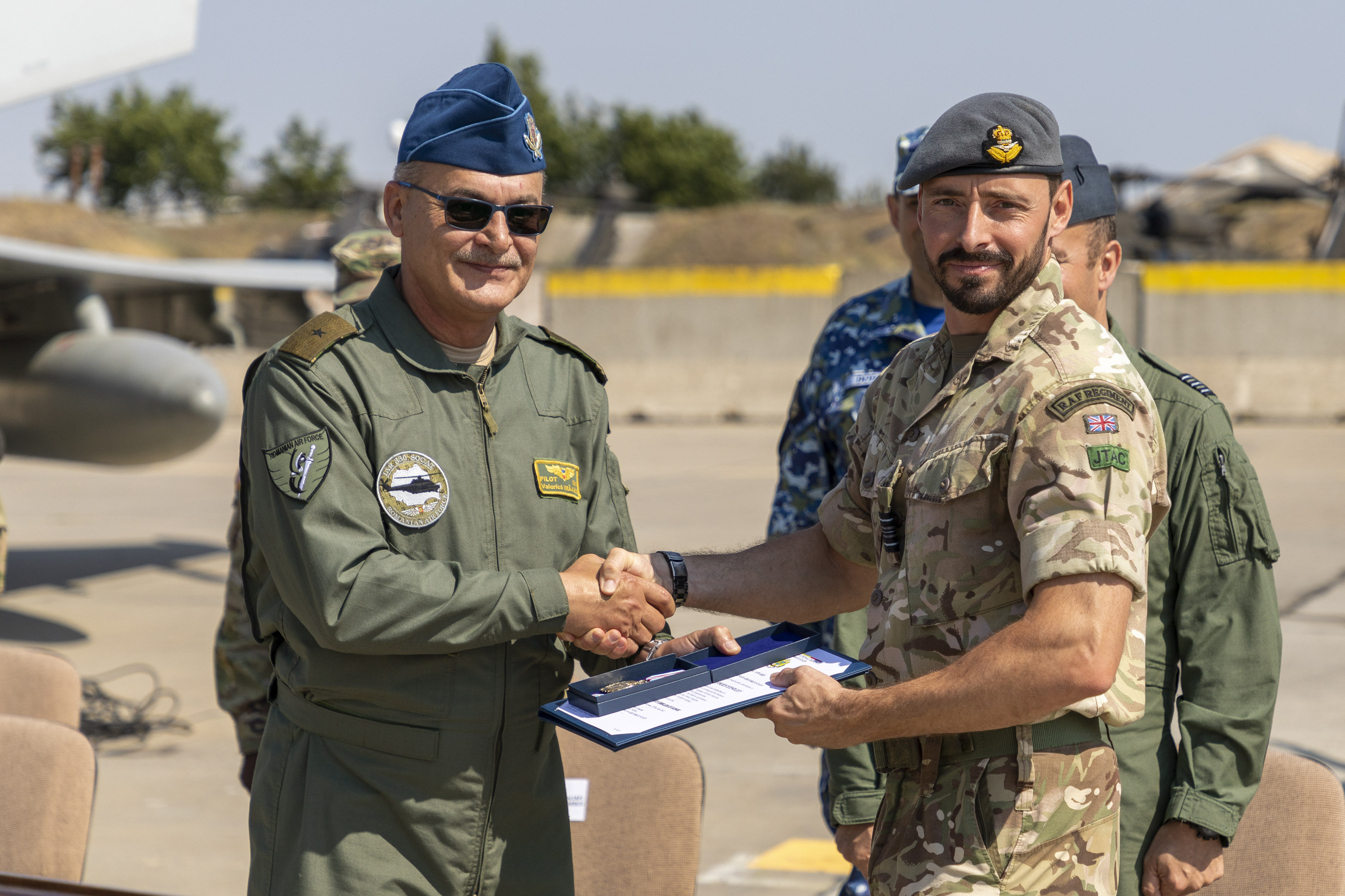Image shows aviators shaking hands with aircraft in the background.
