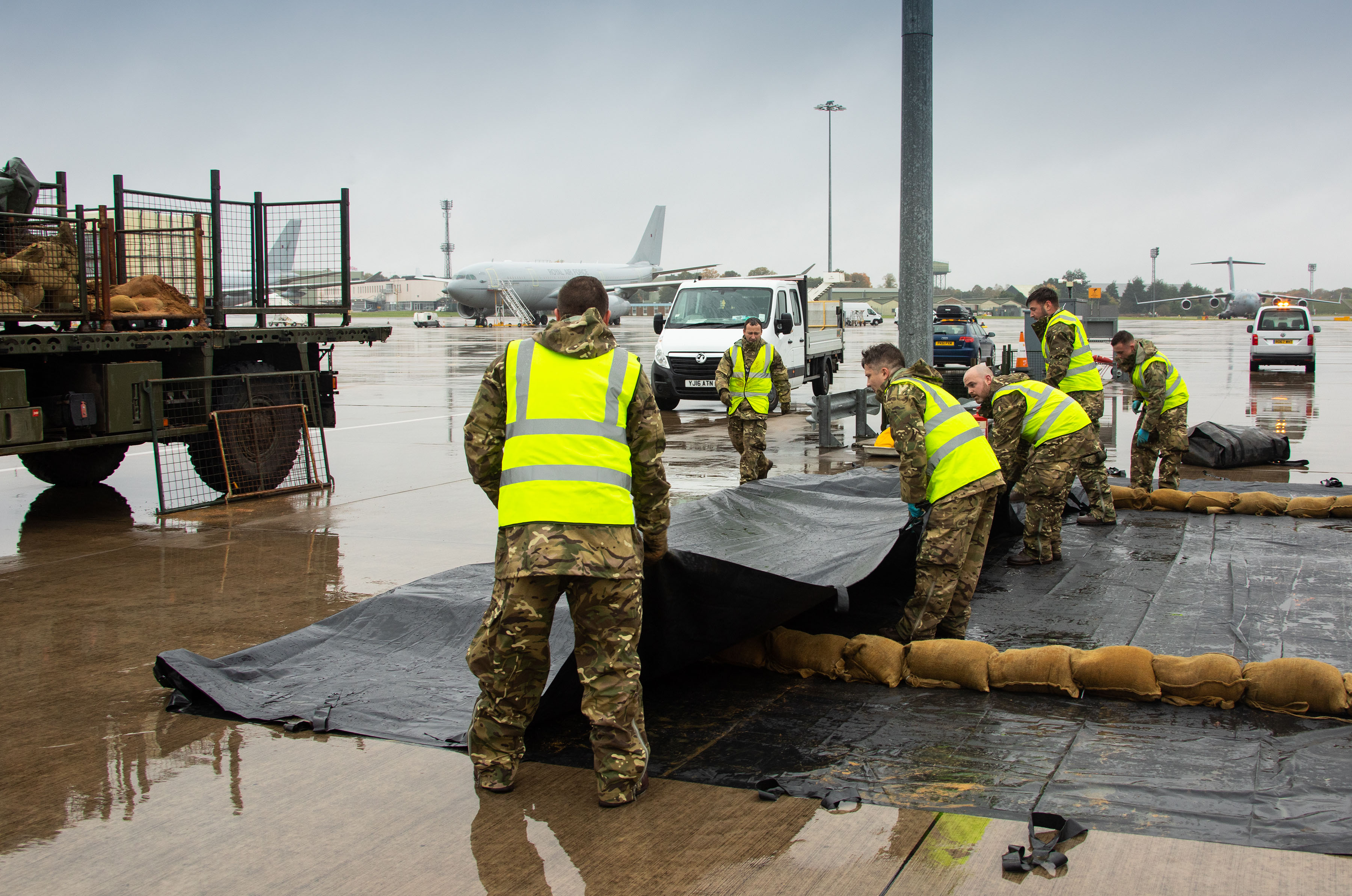 Personnel work with spill kit on the airfield, with vehicles.