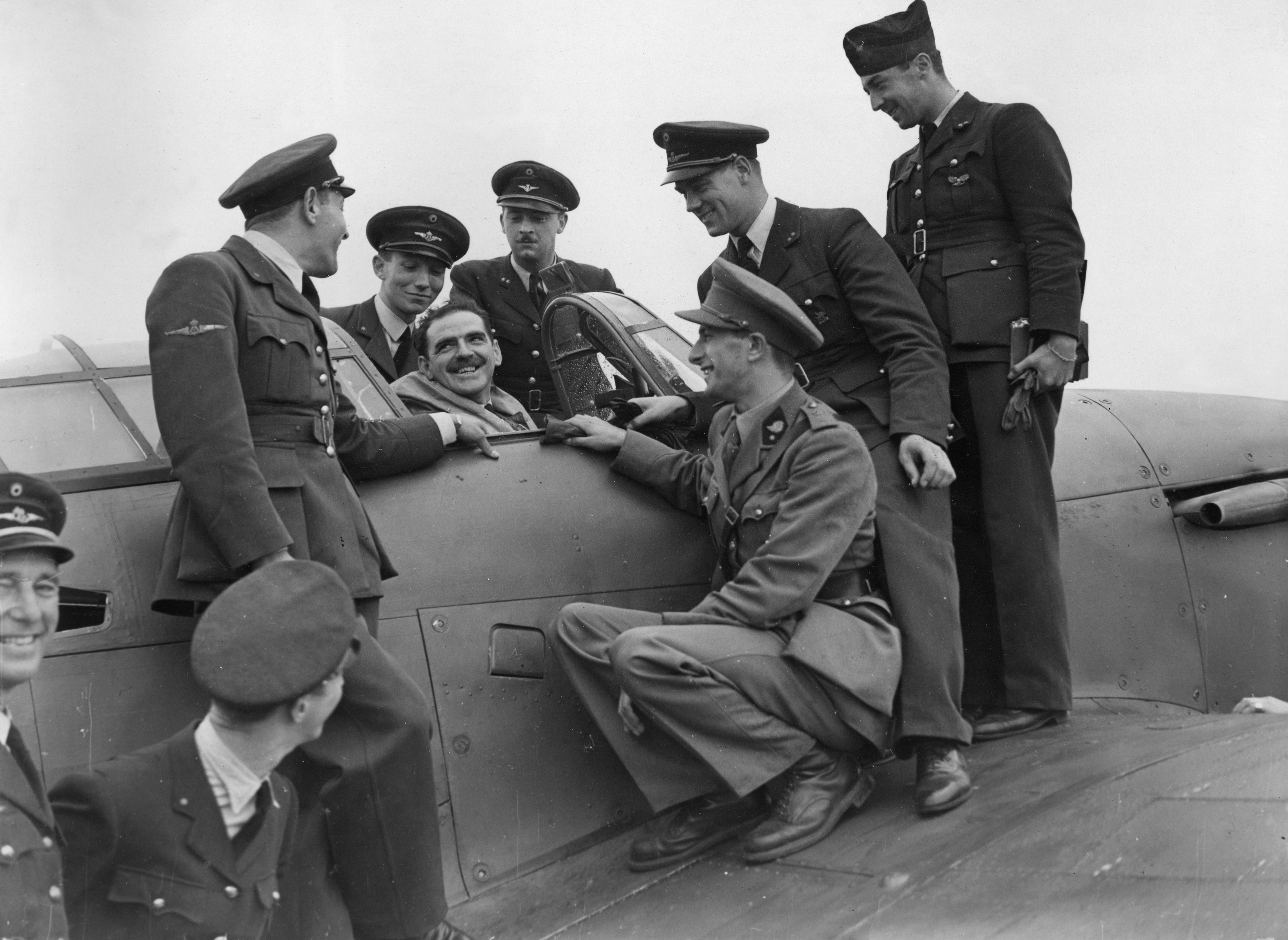 Pilots stand around a Hurricane cockpit.