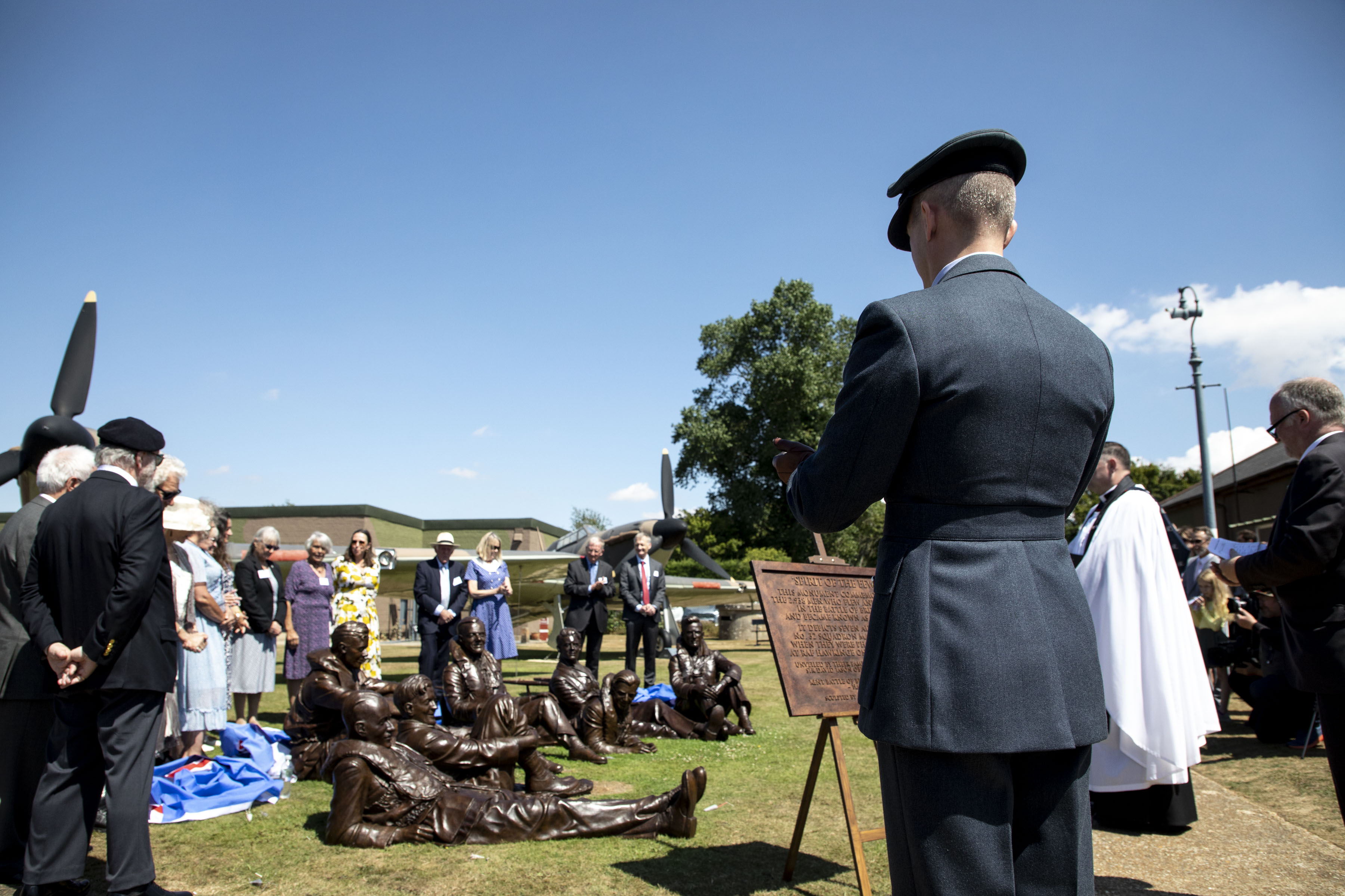 Image shows aviators and members of the public with the bronze sculptures and commemorative plaque