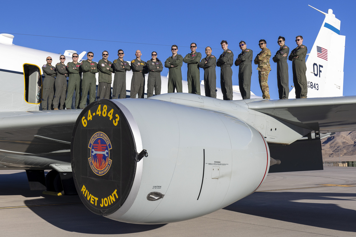Image shows aircrew standing on top of a Rivet Joint aircraft wing.