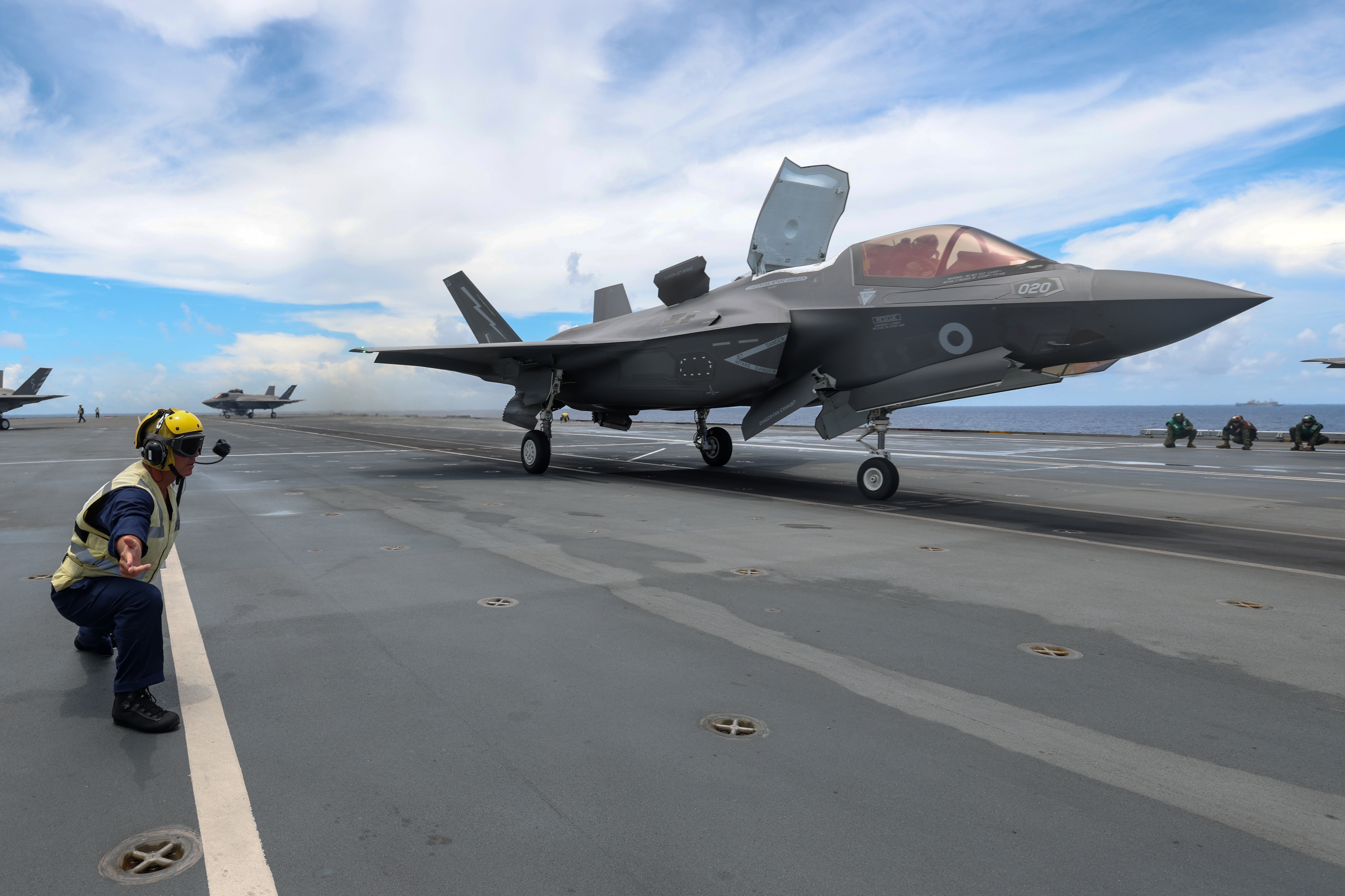 F-35B Lightning on runway being guided by Personnel.