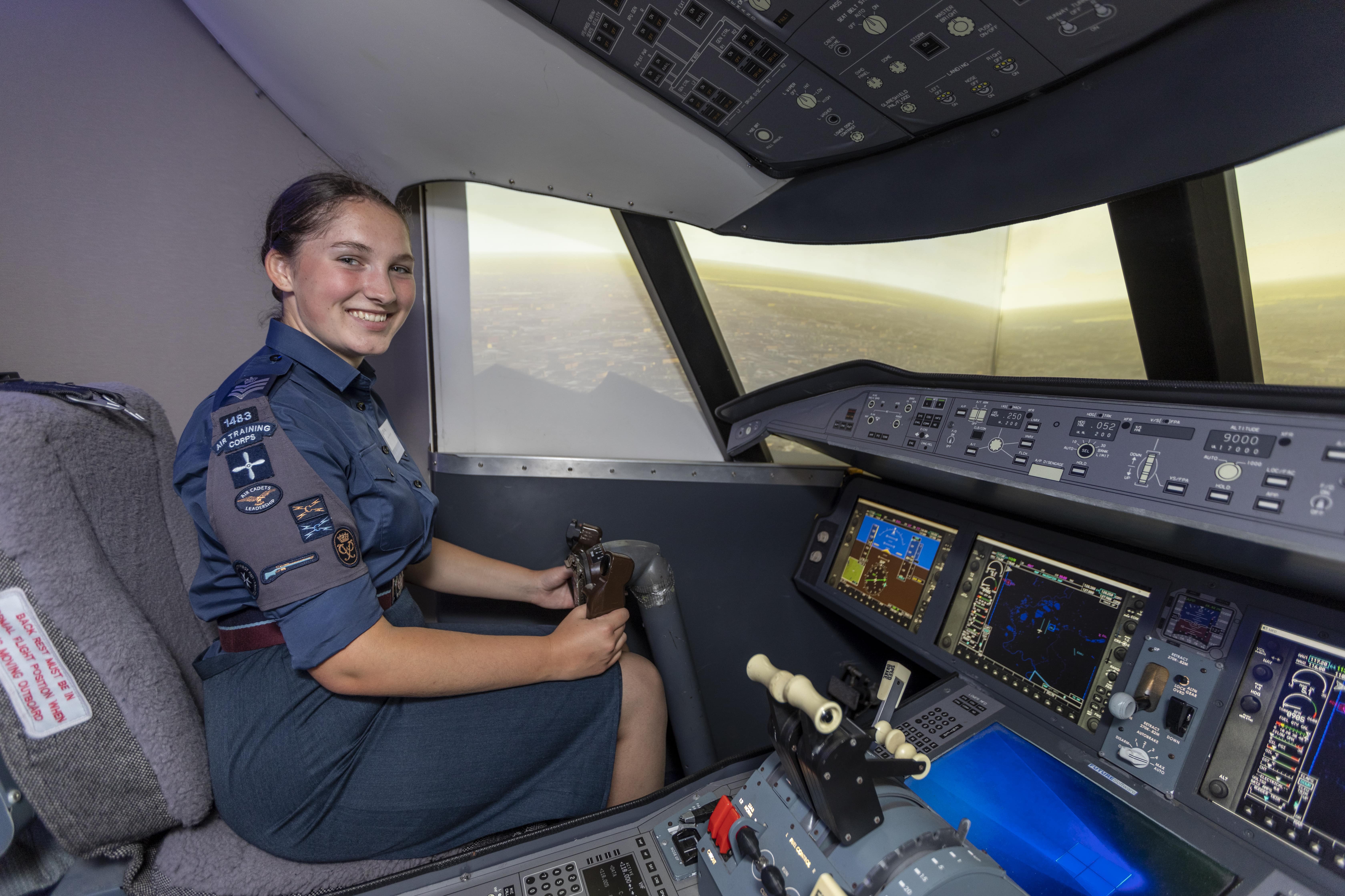 Female cadet in uniform sitting in a flight simulator