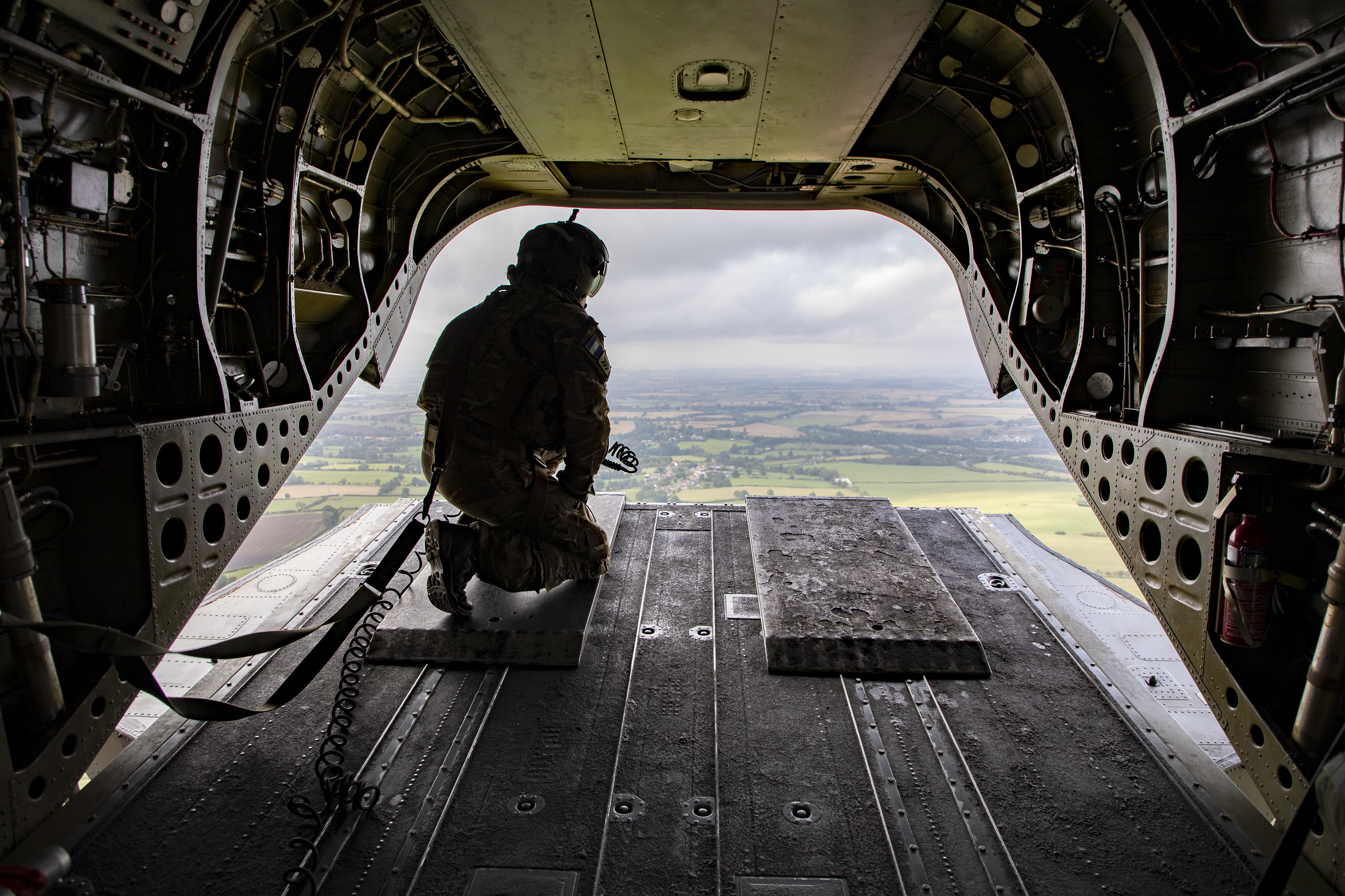 Image shows RAF personnel looking out from loading bay of helicopter as it flies.