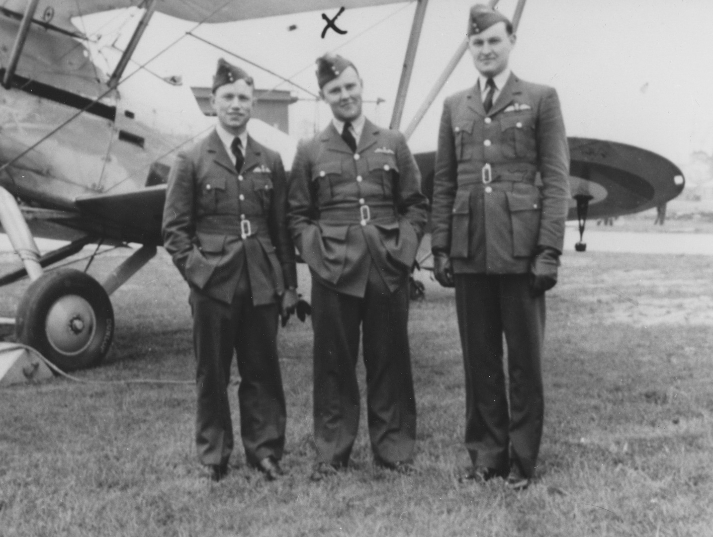 Black and white image shows World War Two RAF personnel standing by the wing of an aircraft.