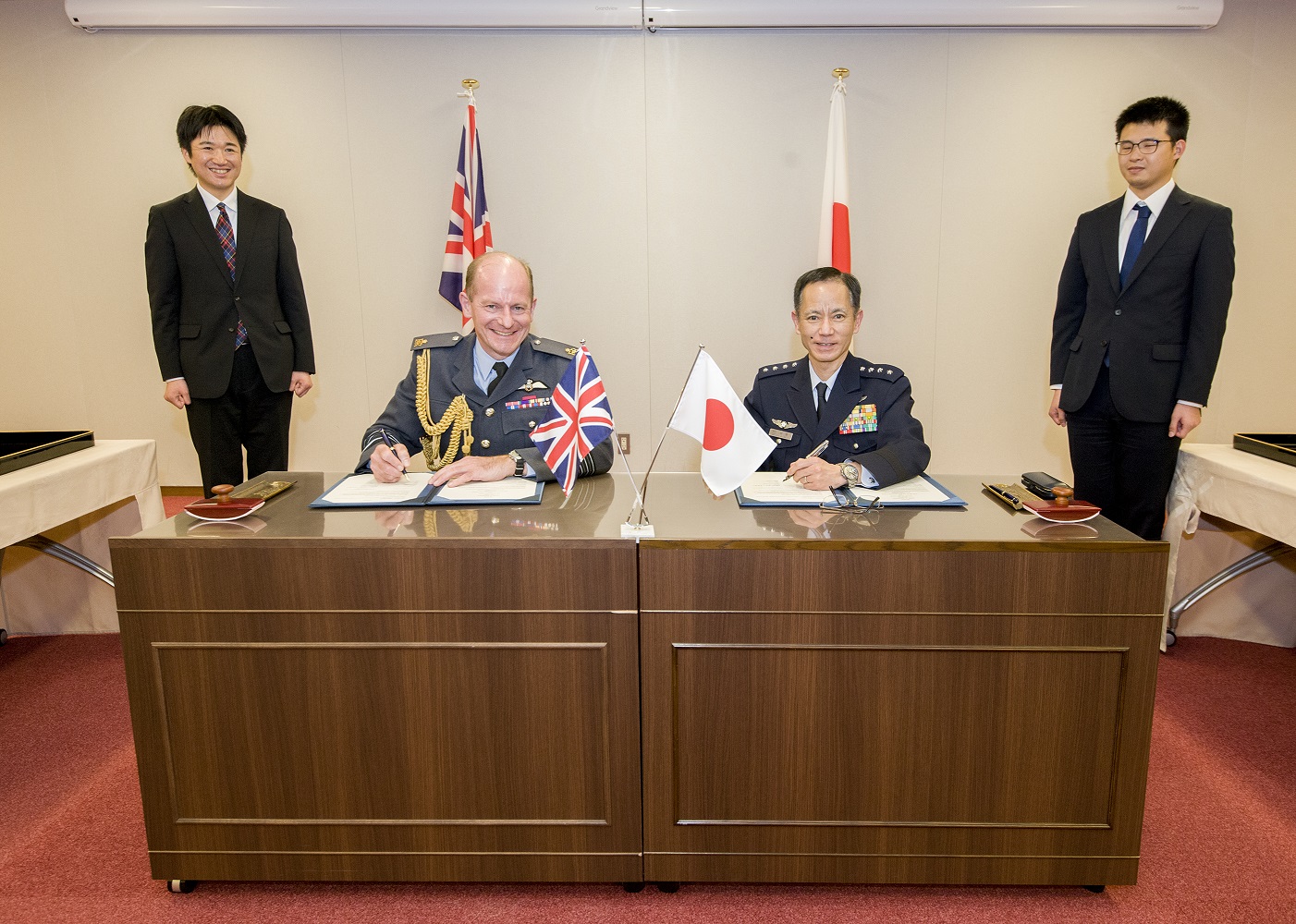 Image shows RAF Chief of Air Staff with Japan Air Self Defence Force, sat at a table signing paper.