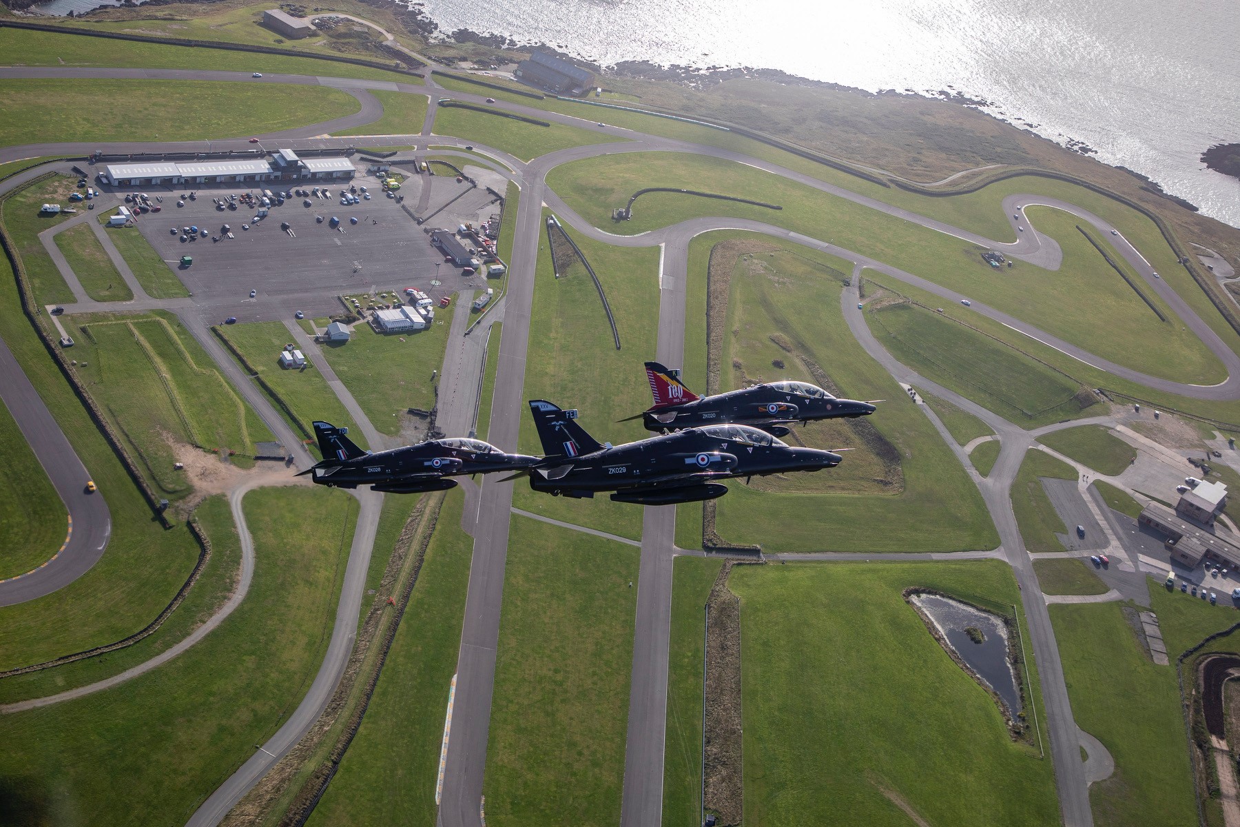 Aerial view of three Hawk T2 aircraft flying over RAF Valley. 