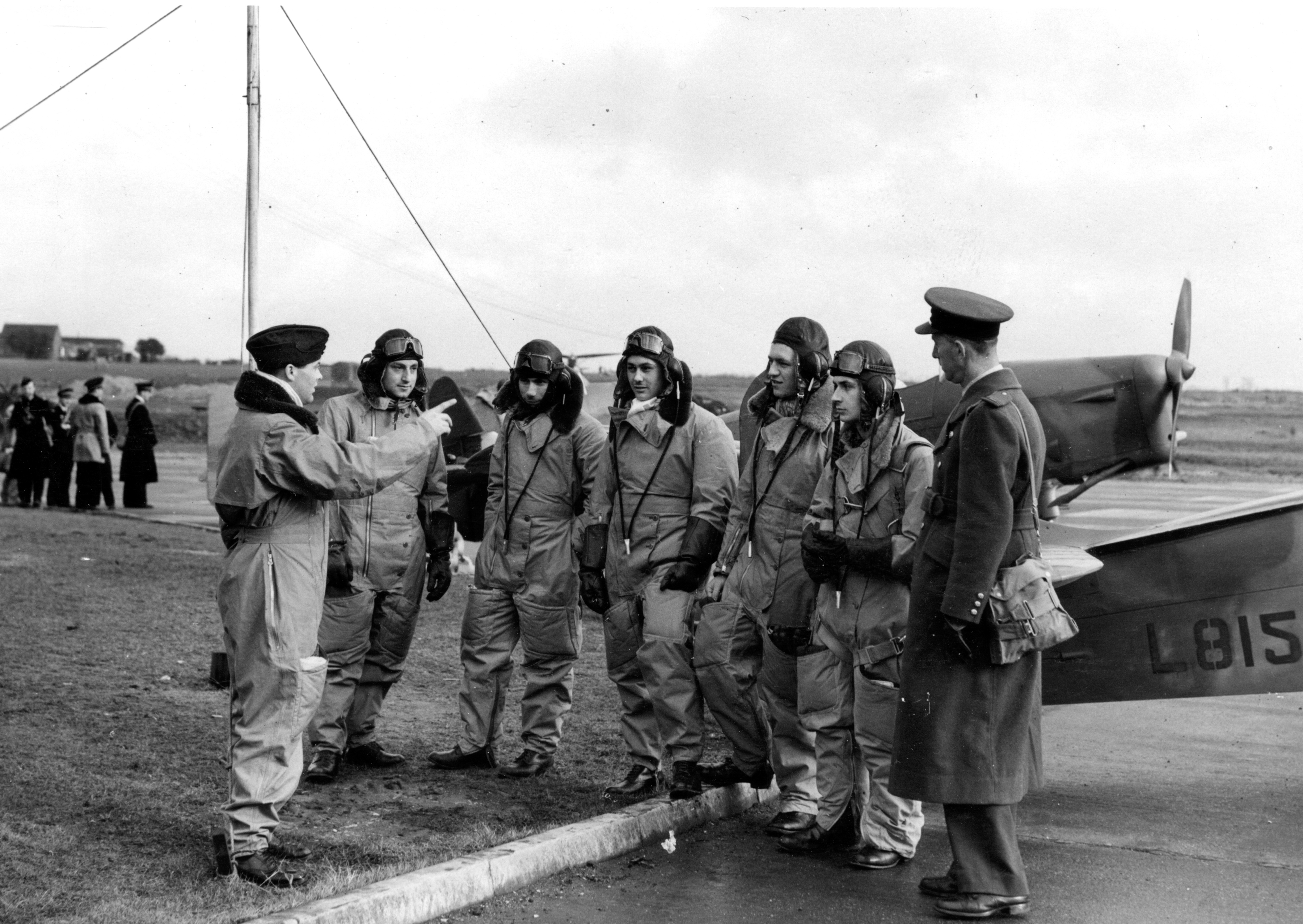 Airmen stand in a group by their Spitfire. 