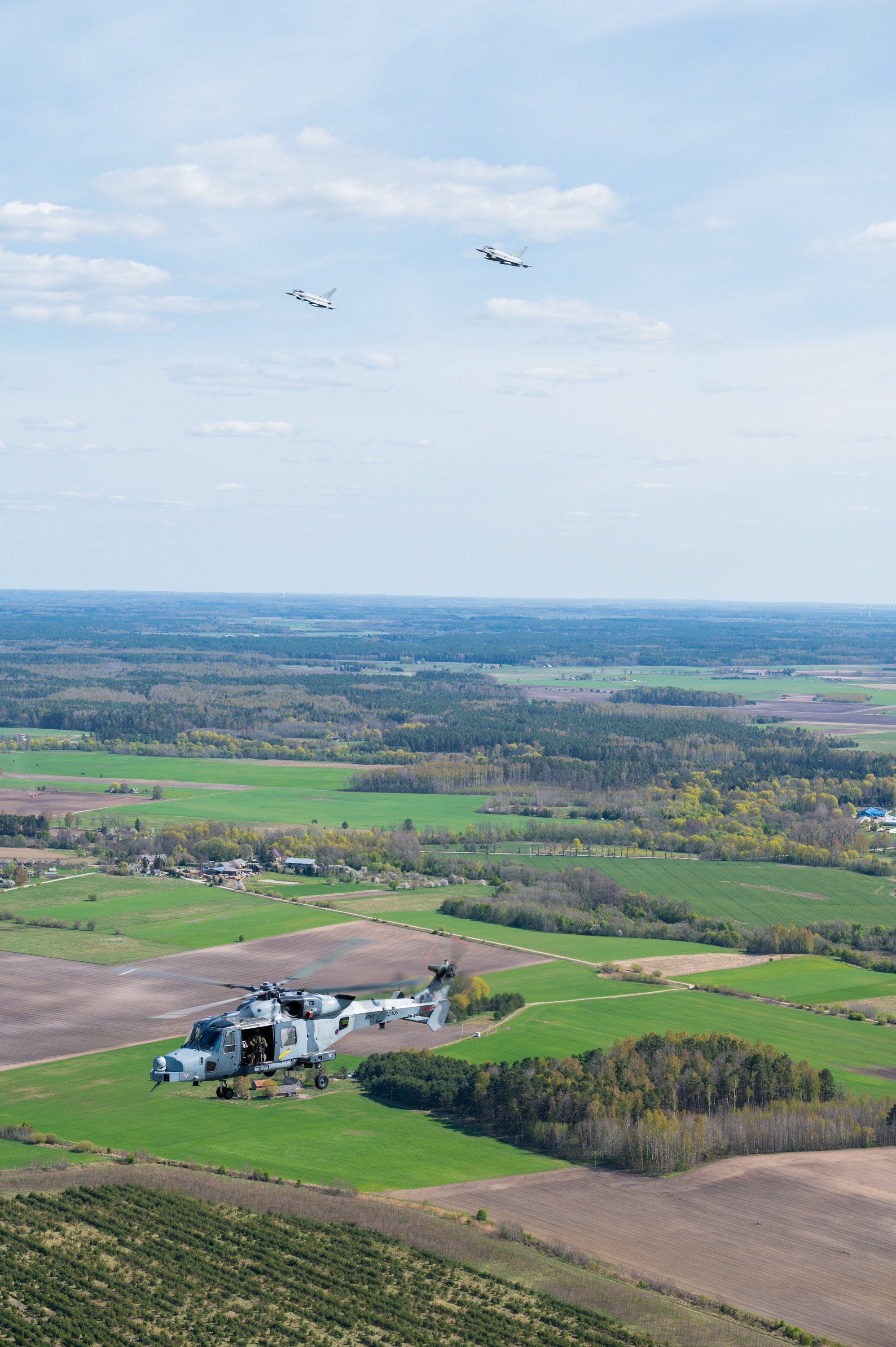 Two RAF Typhoons and a British Army Wildcat helicopter in flight.