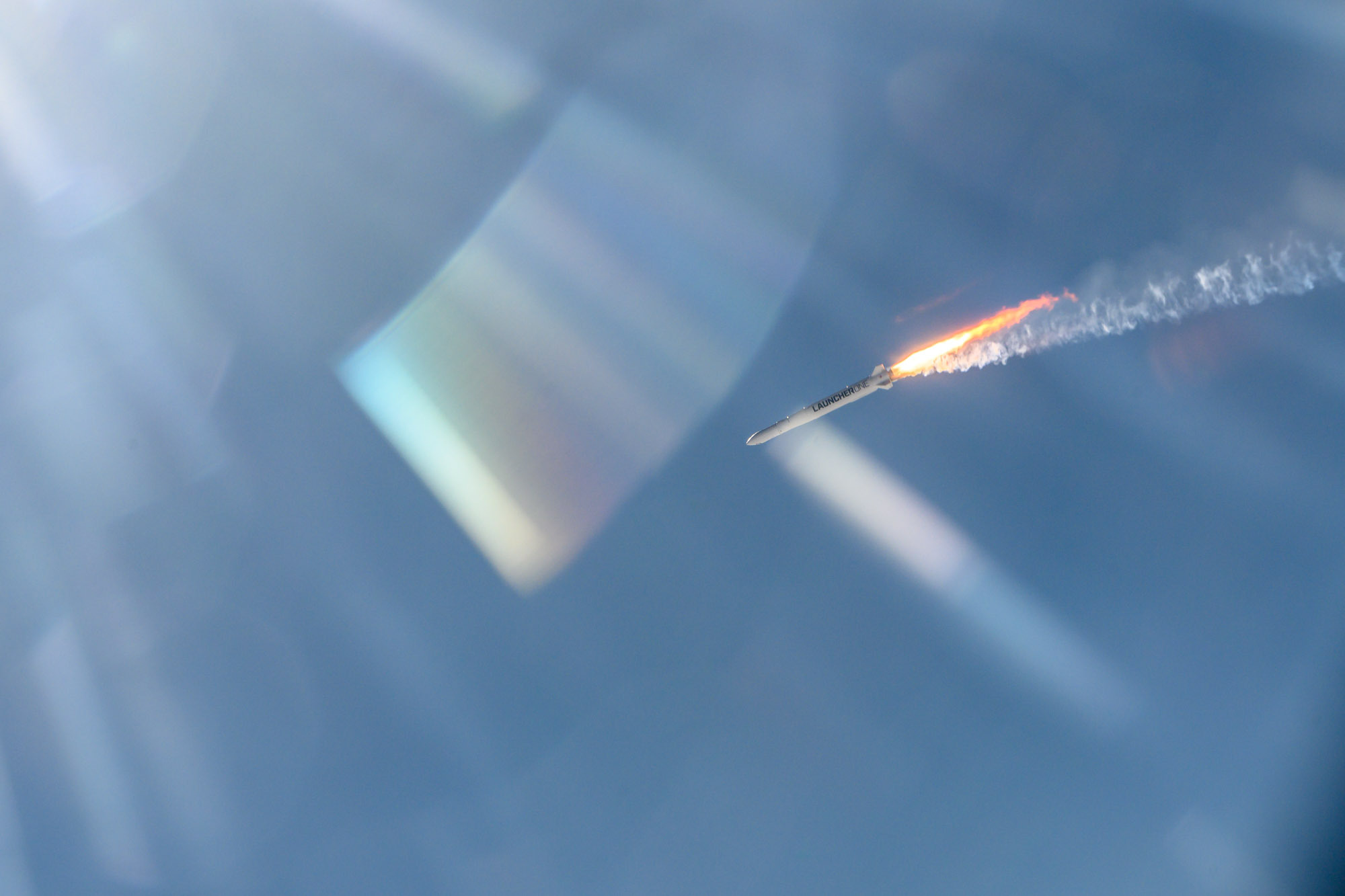 Rocket in the sky, with sunlight rays blurring view.