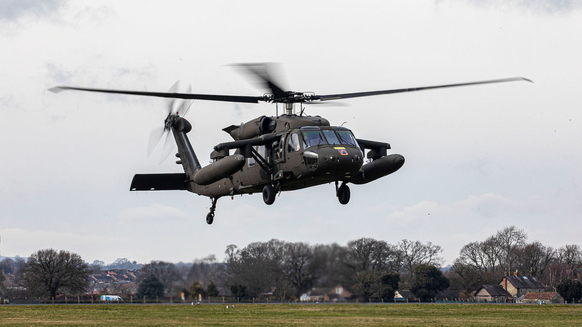Image shows helicopter flying over airfield.
