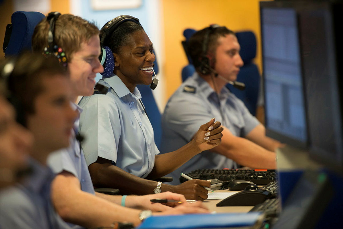 Personnel wear headset at computer desks.