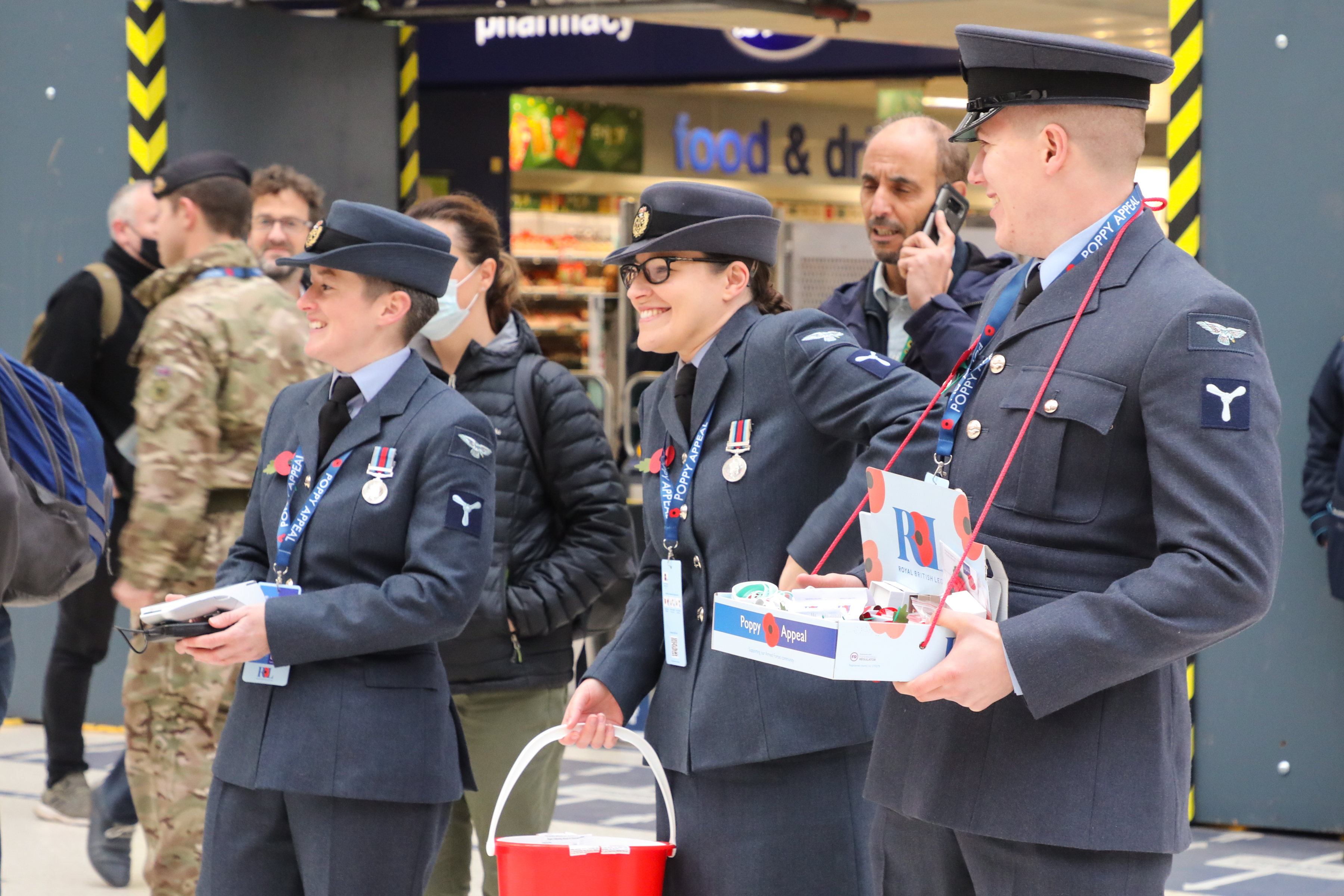 Personnel stand in a shopping centre with Poppy bucket collections and Ross Kemp.